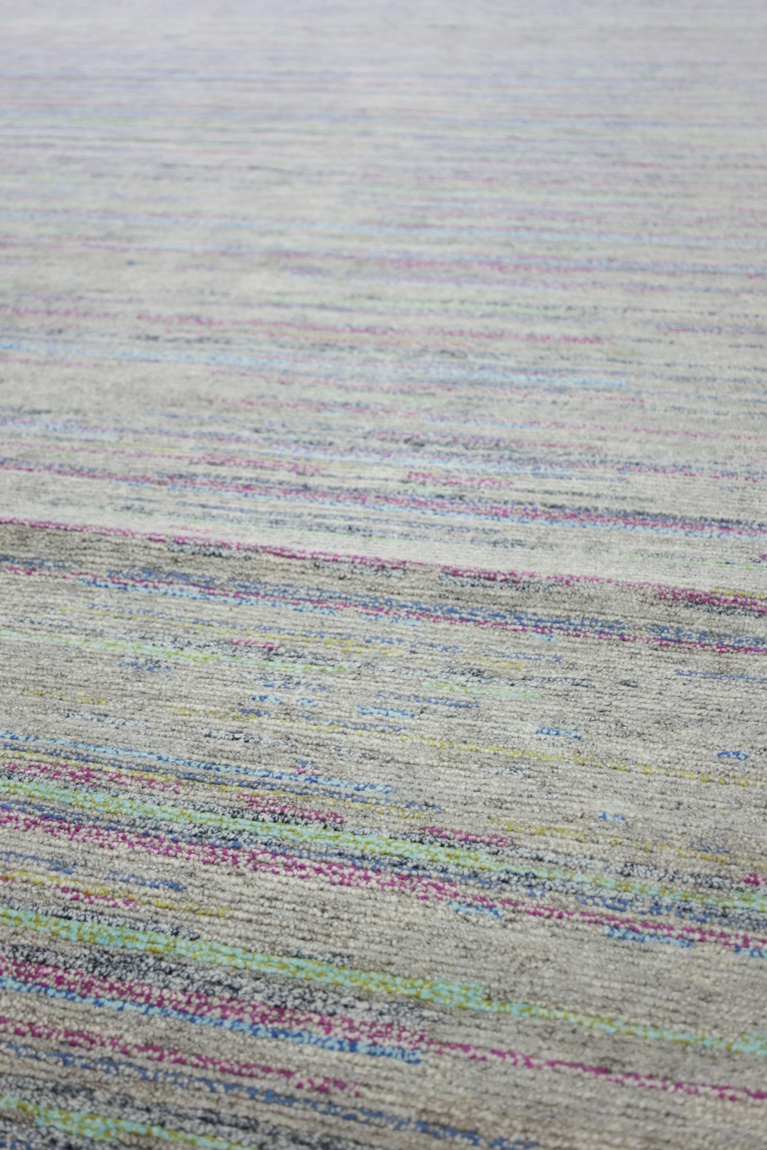 Handwoven rug detail: multicolored stripes on a neutral base, showcasing contemporary design.
