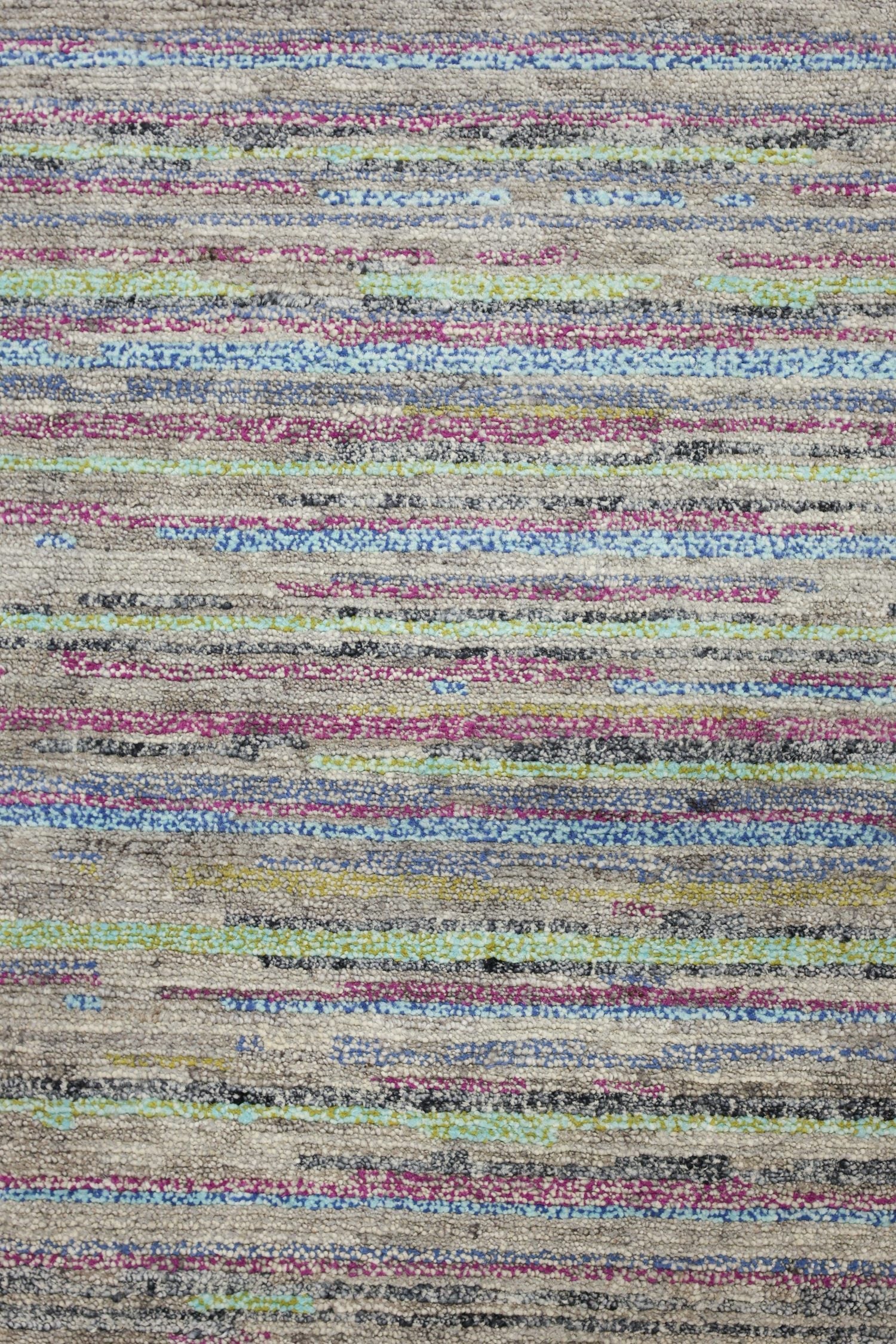 Handwoven rug detail: multicolored stripes in teal, pink, and gray on a neutral background.
