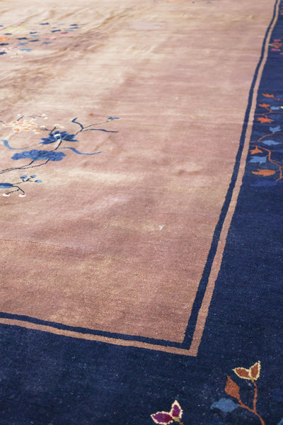 Antique handwoven rug detail:  Beige field with floral pattern, navy blue border.
