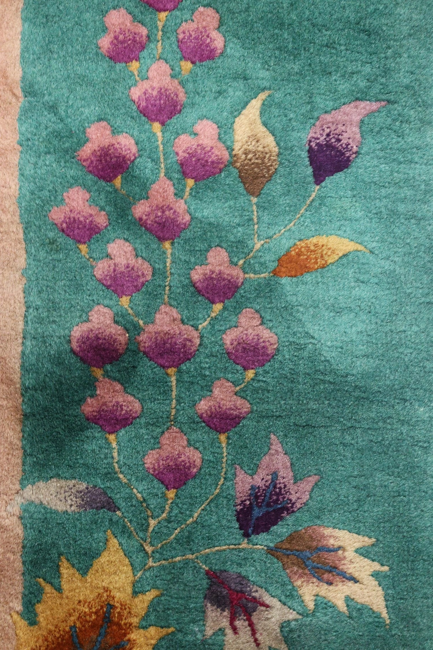 Teal handwoven rug detail: Art Deco floral pattern in pink, purple, and gold accents.
