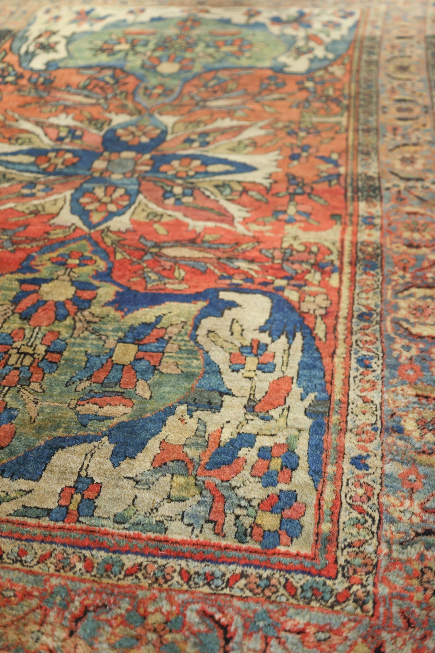 Handwoven Farahan Sarouk rug detail, showcasing intricate floral and geometric patterns in muted reds, blues, and creams.
