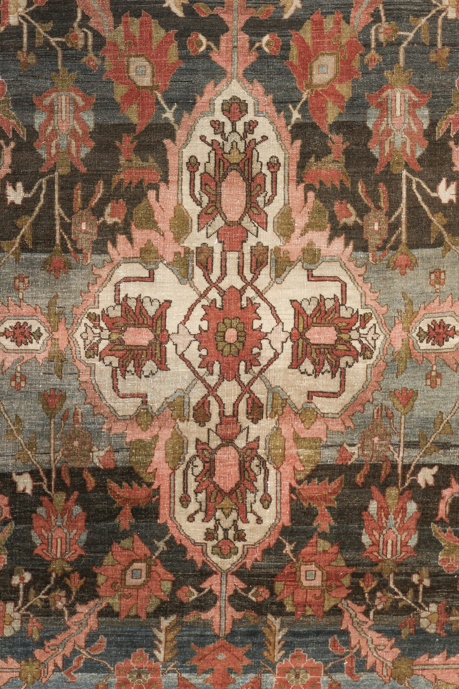 Detailed view of a traditional handwoven rug with a floral pattern in muted reds, pinks, and greens on a dark background.
