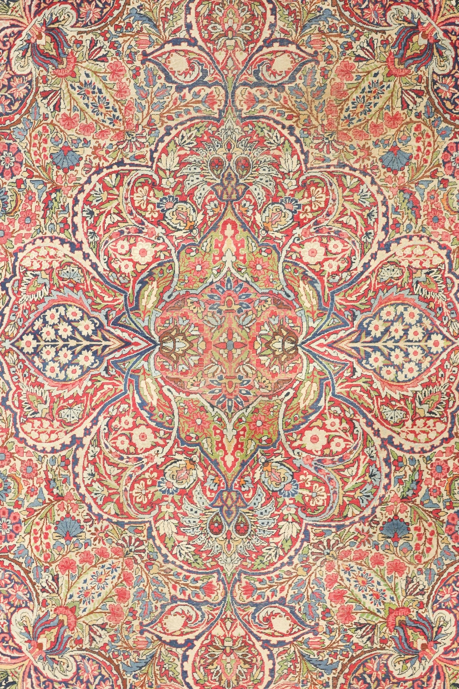 Intricate antique rug displaying a traditional floral paisley pattern in muted reds, blues, and creams.
