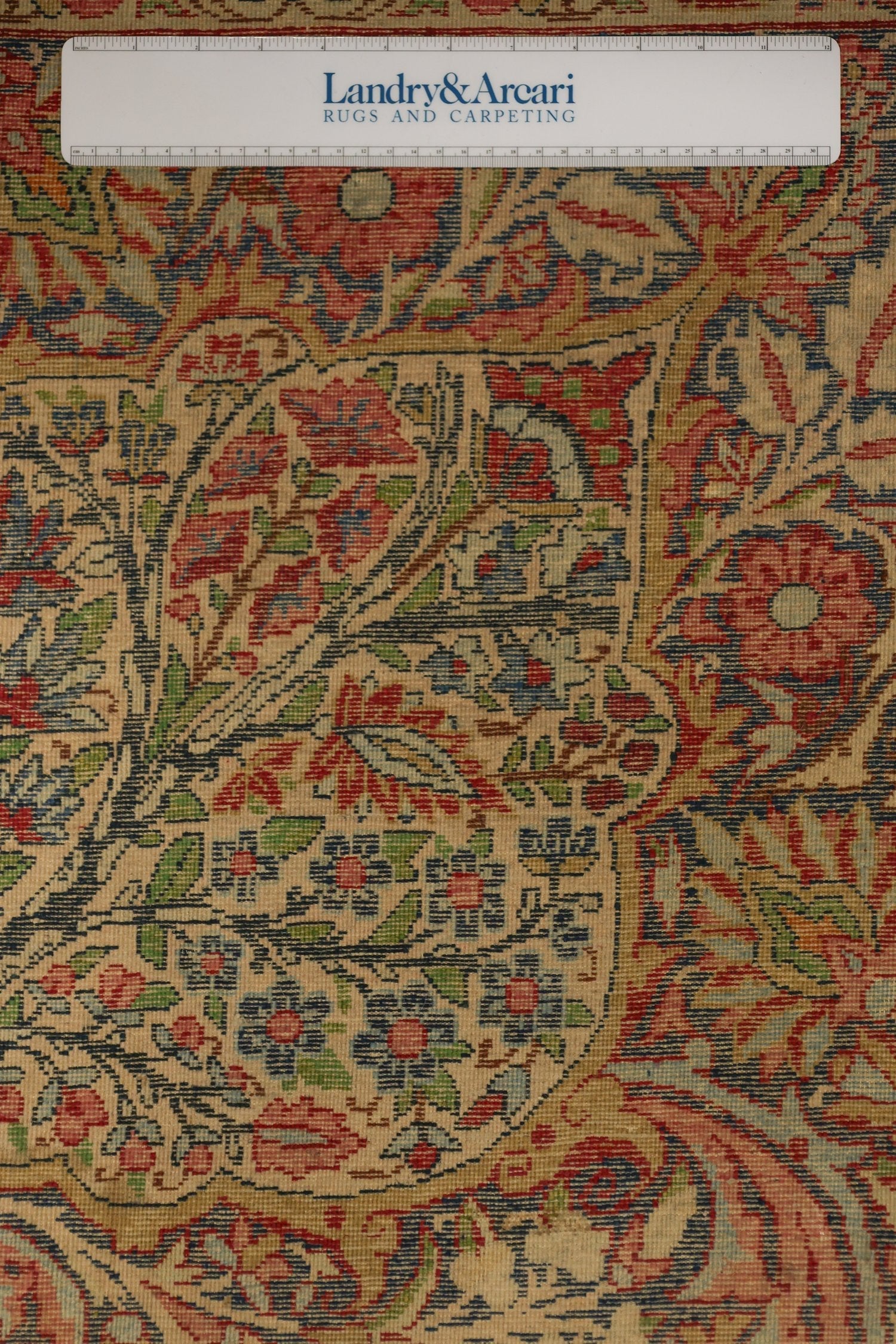 Close-up detail of antique Kerman rug's intricate floral pattern, showcasing handwoven craftsmanship and muted colors.
