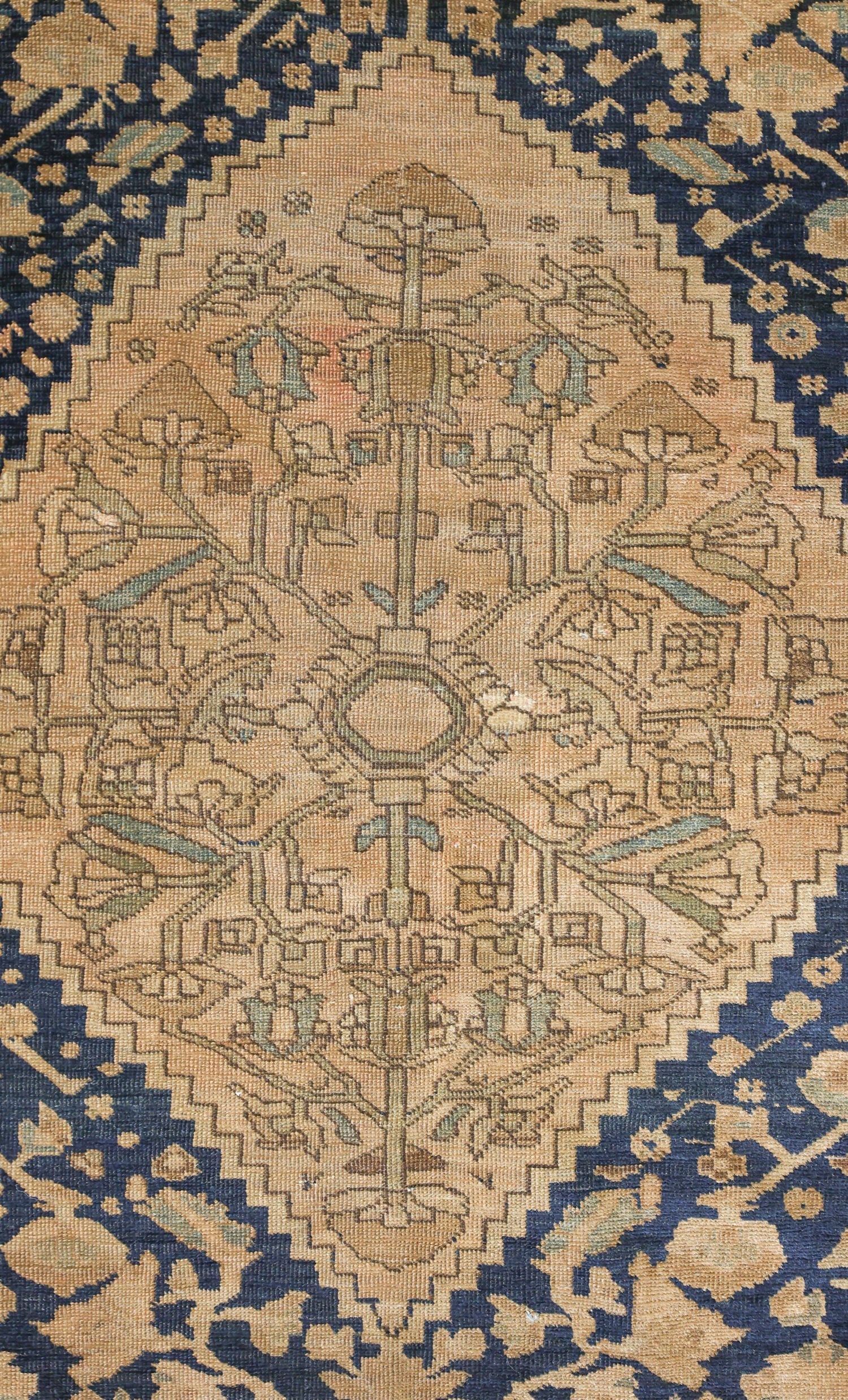 Detail of antique rug's handwoven, beige and navy floral pattern.
