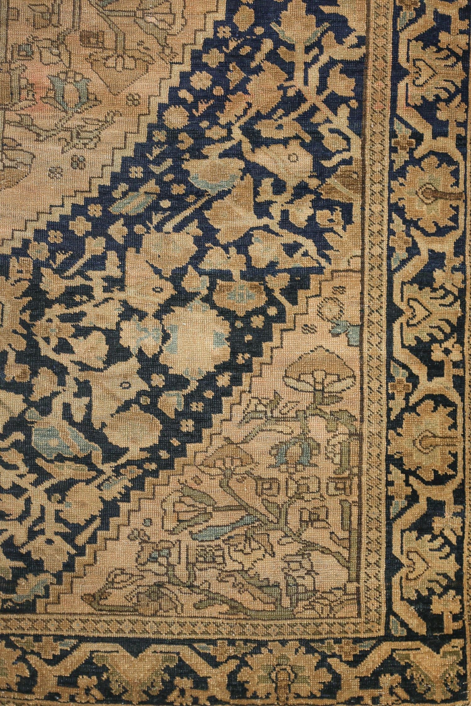 Handwoven antique rug detail, showcasing beige and navy floral pattern.
