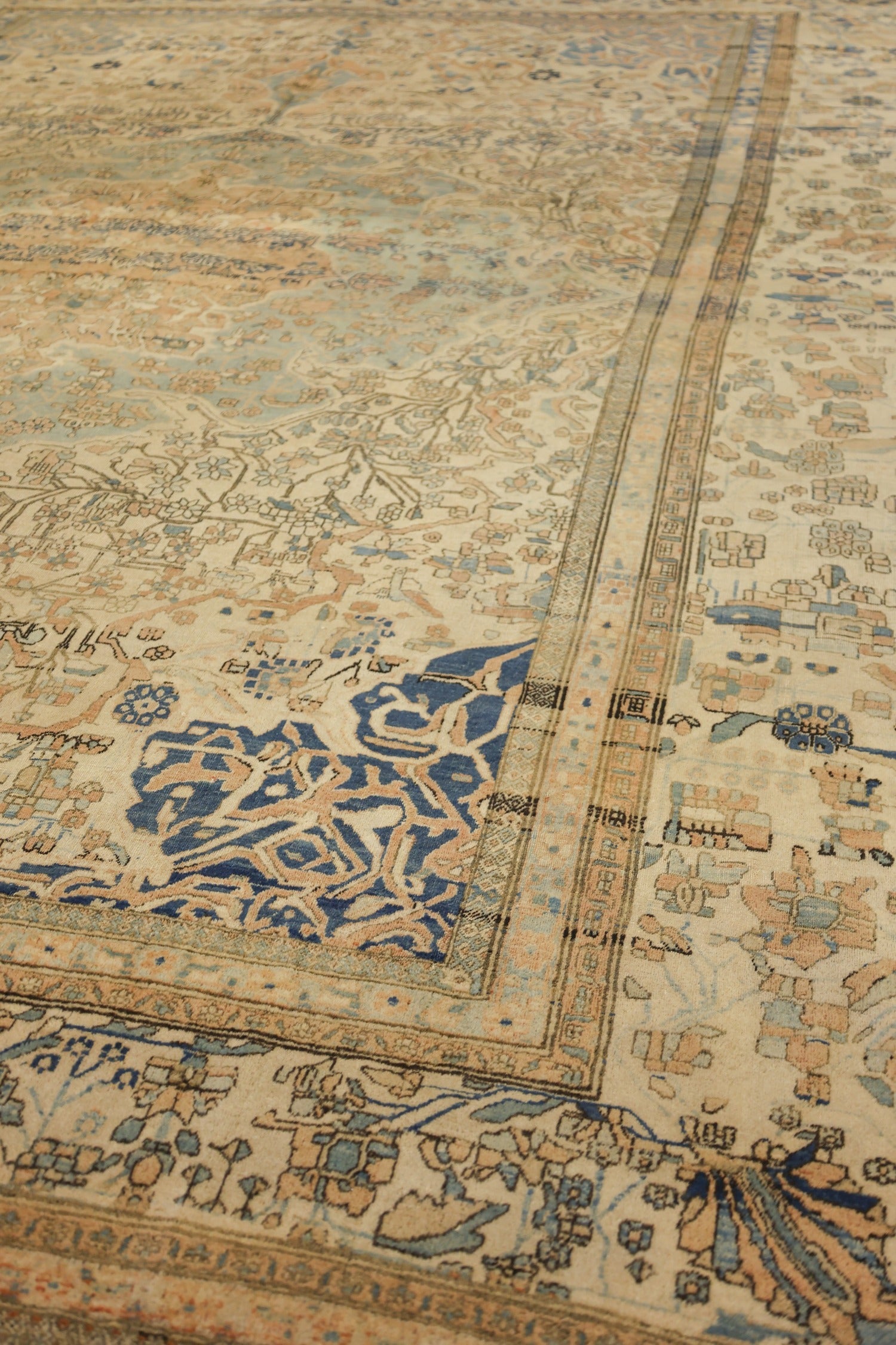 Close-up of antique Kashan rug's intricate, handwoven design; muted blues and beige tones.
