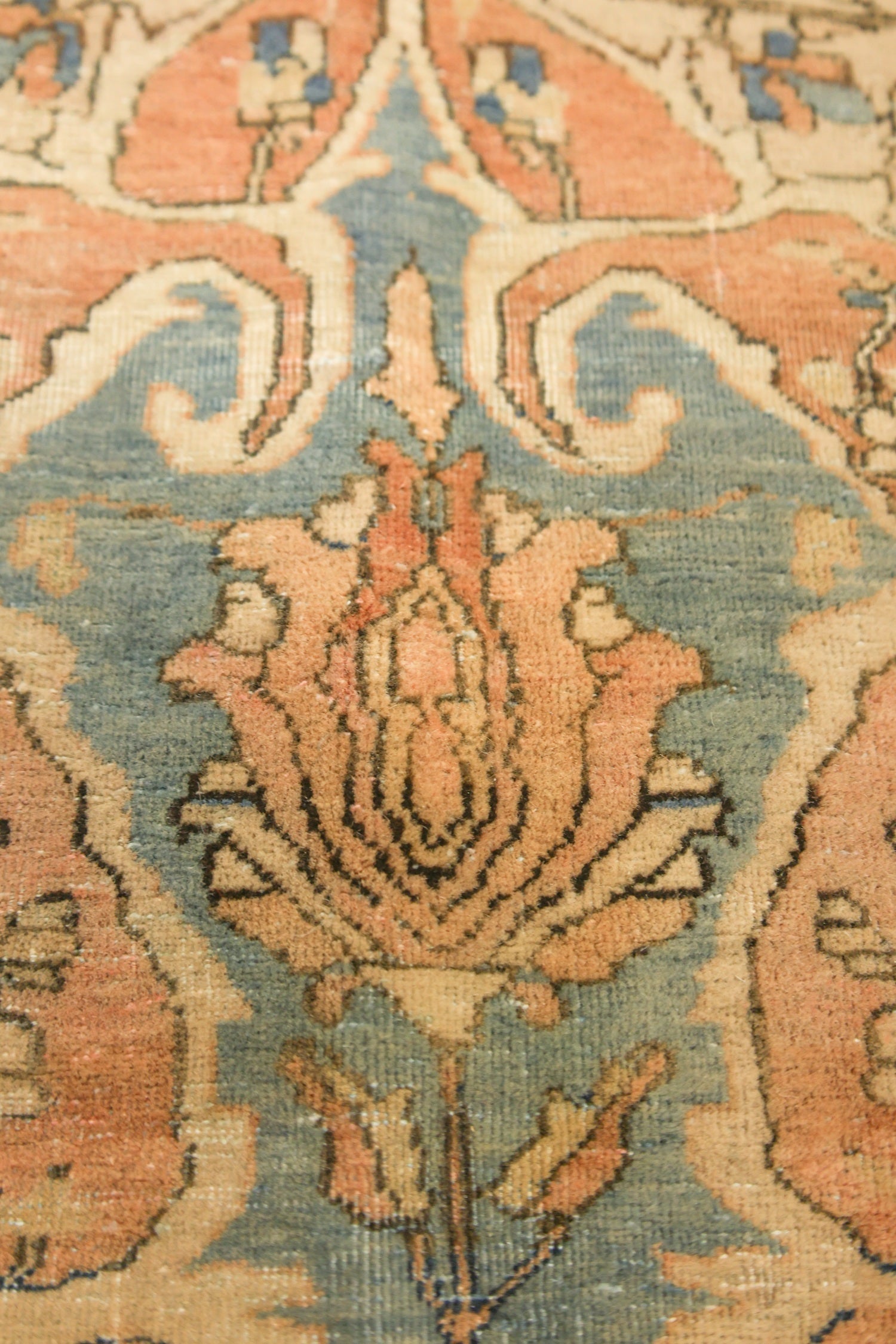 Close-up of antique Kashan rug detail, showcasing a floral pattern in muted peach and teal tones.
