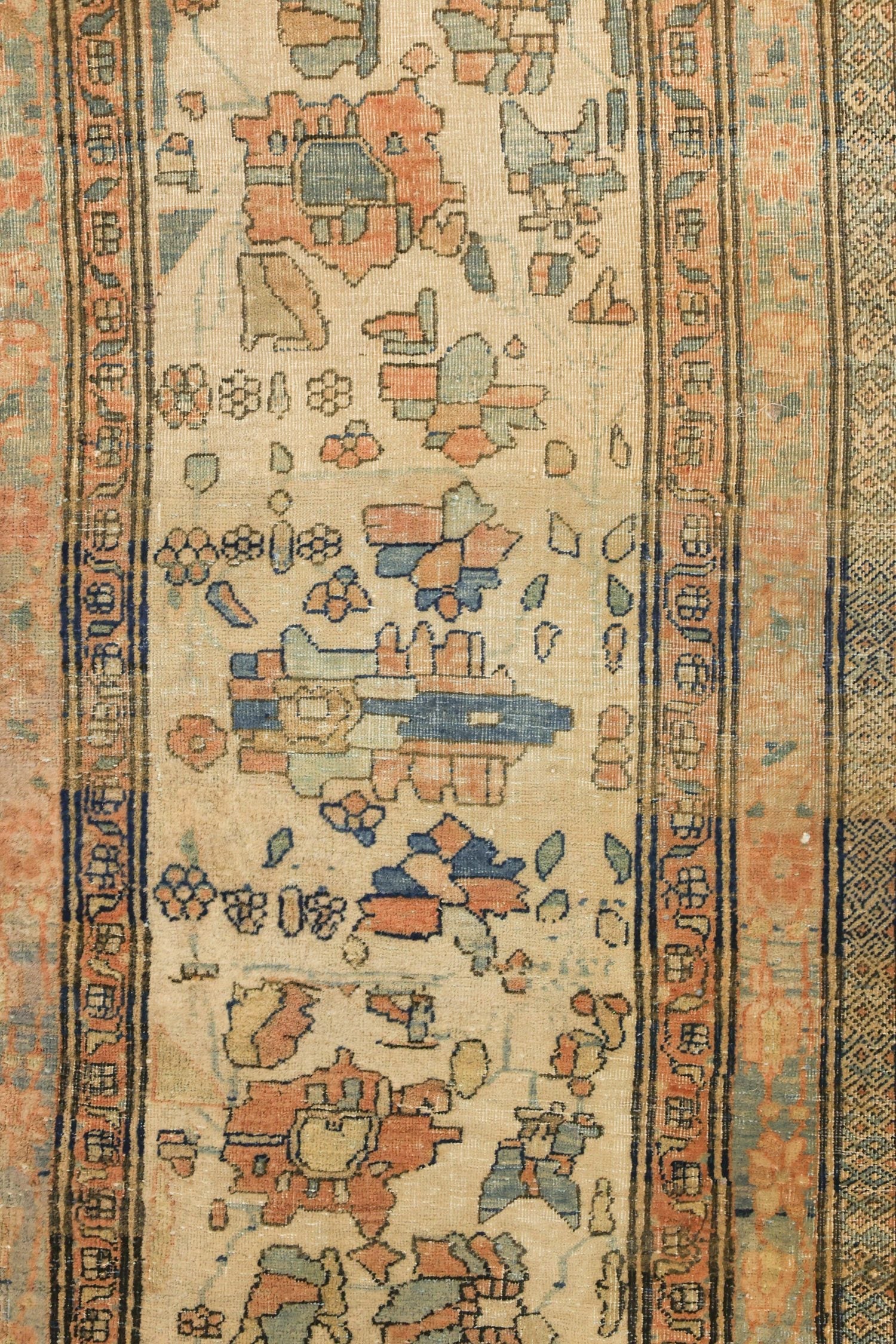 Detail of antique Kashan rug, featuring a beige field with muted floral and geometric patterns in coral, teal, and navy.
