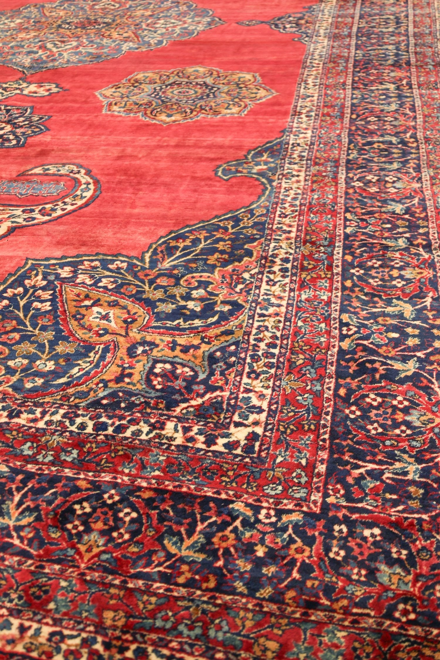 Intricate red and navy handwoven rug detail, showcasing traditional Persian floral patterns.
