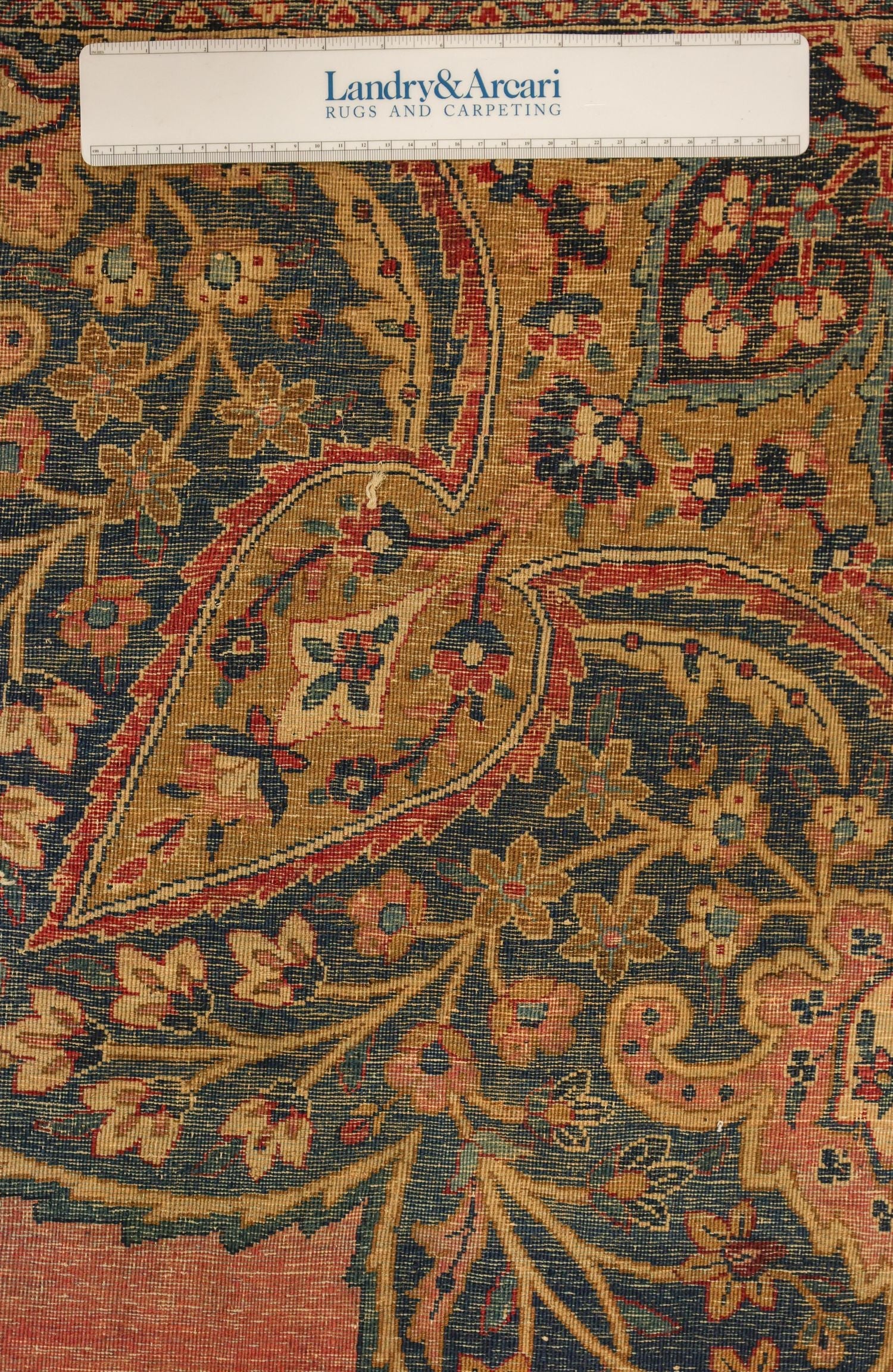 Close-up detail of antique Kerman rug's intricate floral pattern, showcasing handwoven craftsmanship and rich color palette.
