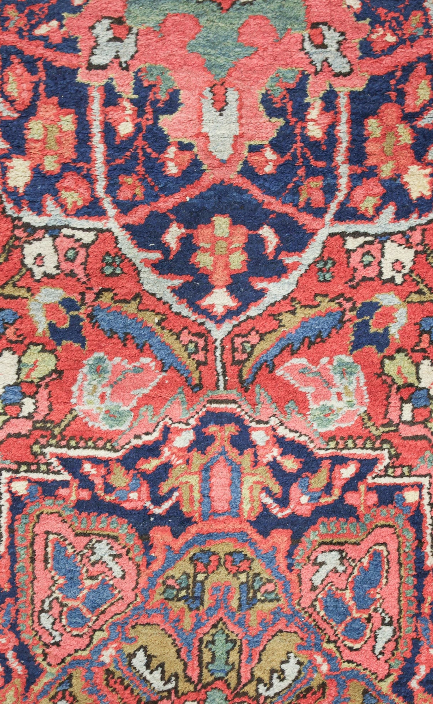 Close-up of antique rug's handwoven, vibrant red and blue tribal pattern.
