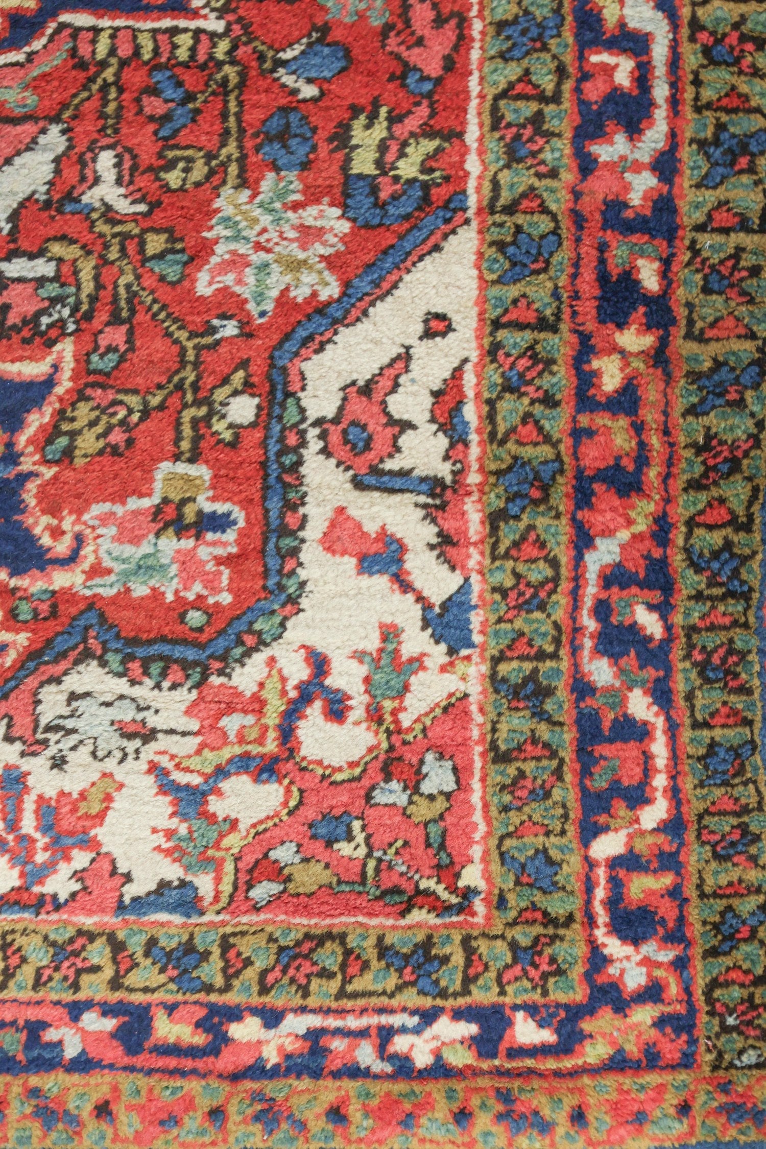 Handwoven tribal rug detail: vibrant red, blue, and cream pattern, antique Ahar Heriz design.
