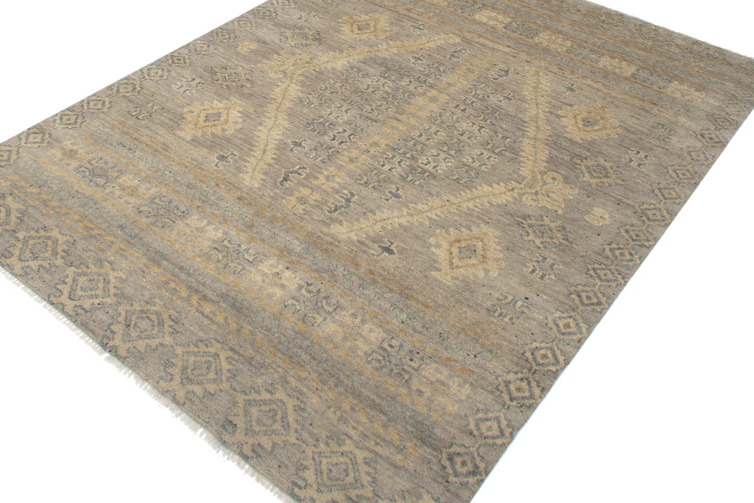 Handwoven rug in beige and gray tones, featuring an intricate tribal pattern.
