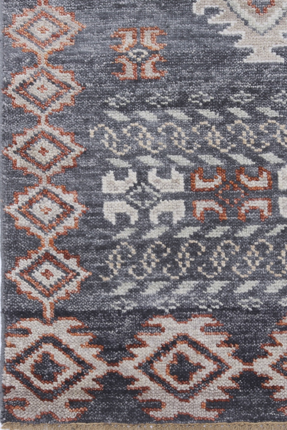 Handwoven rug detail, gray base with burnt orange and off-white tribal patterns.
