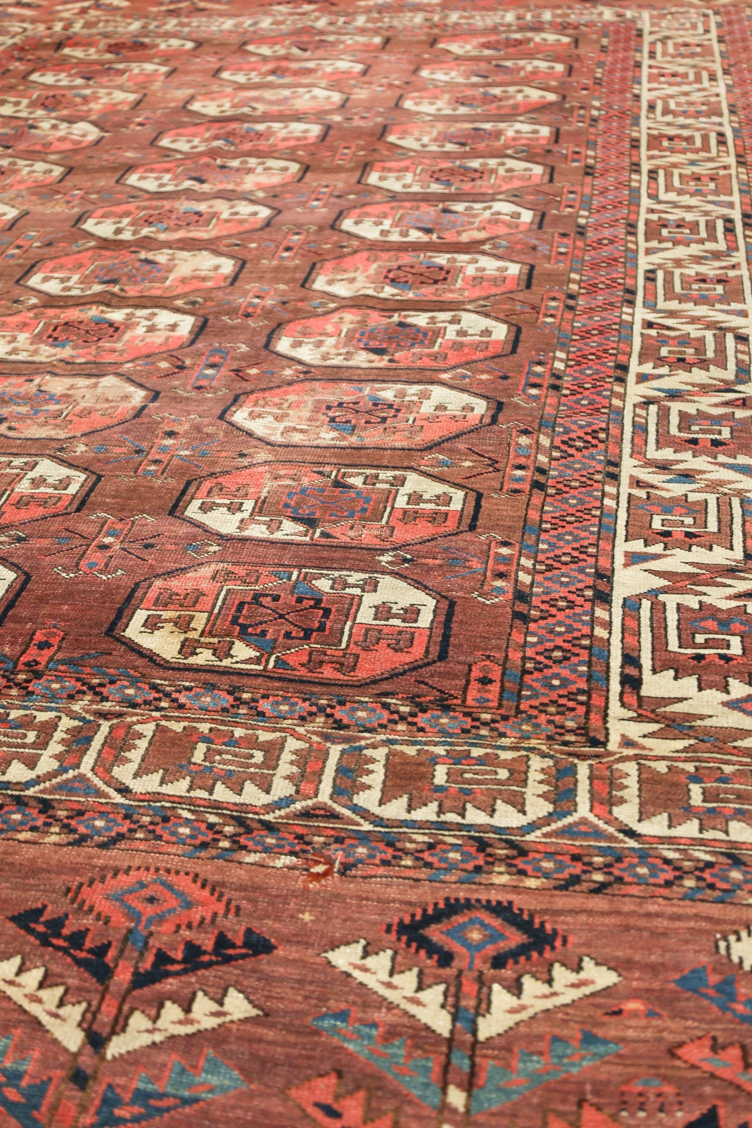 Handwoven tribal rug detail, showcasing rich red and beige tones with intricate geometric patterns.
