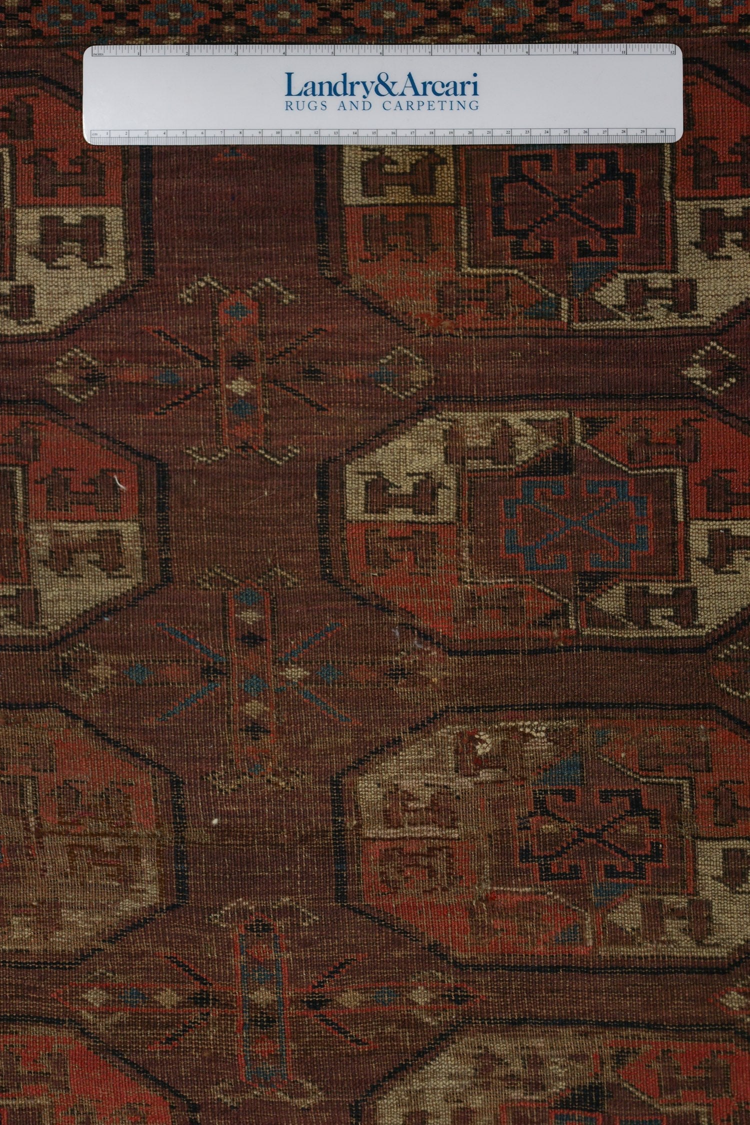 Close-up detail of an antique Arabachi rug's handwoven, geometric pattern in muted reds and browns.
