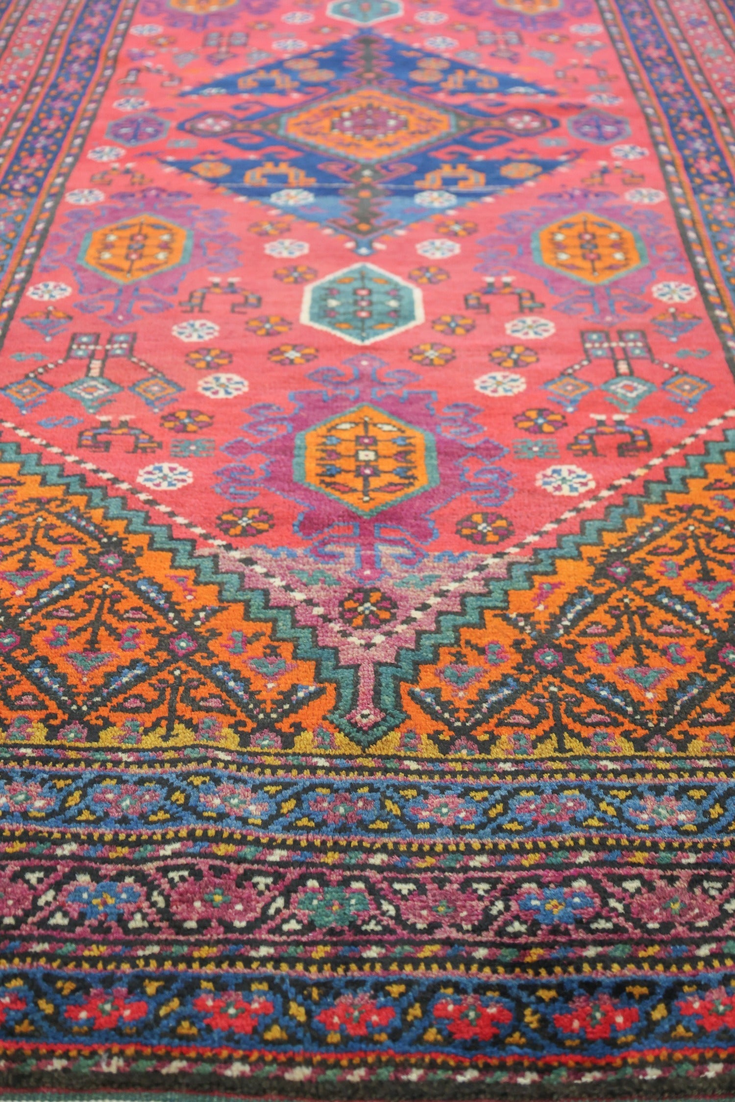 Close-up of a vibrant, handwoven rug showcasing intricate tribal patterns in reds, oranges, and blues.
