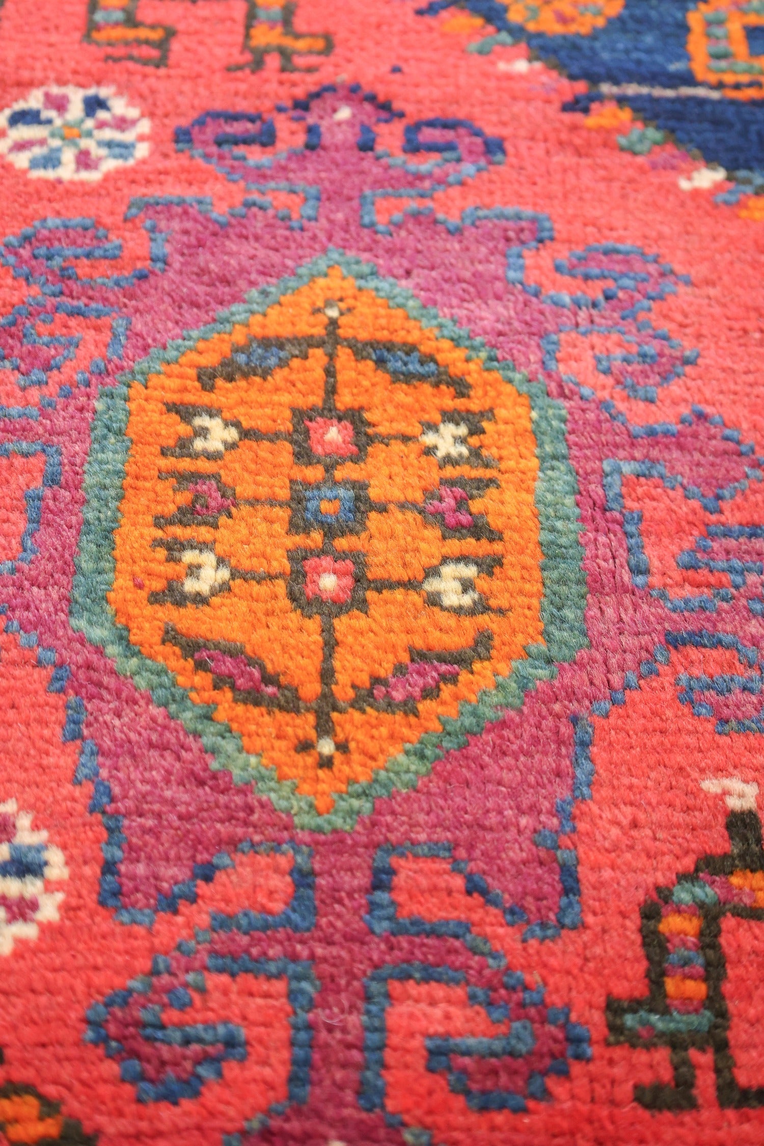 Close-up of vibrant, handwoven rug detail; rich reds, oranges, and blues in a traditional tribal design.
