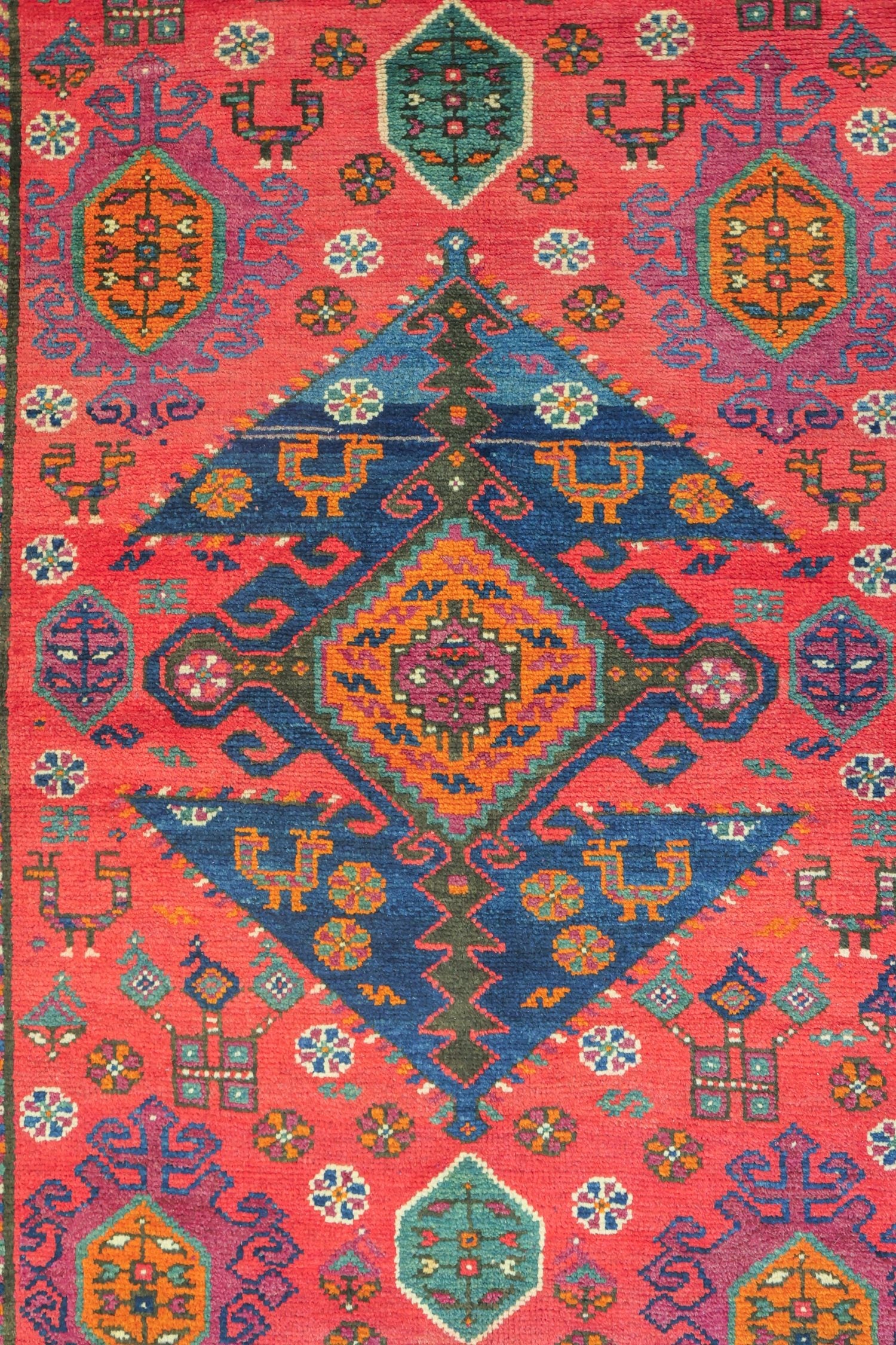 Vibrant coral-red antique rug showcasing intricate Azeri tribal designs in navy, teal, and orange.
