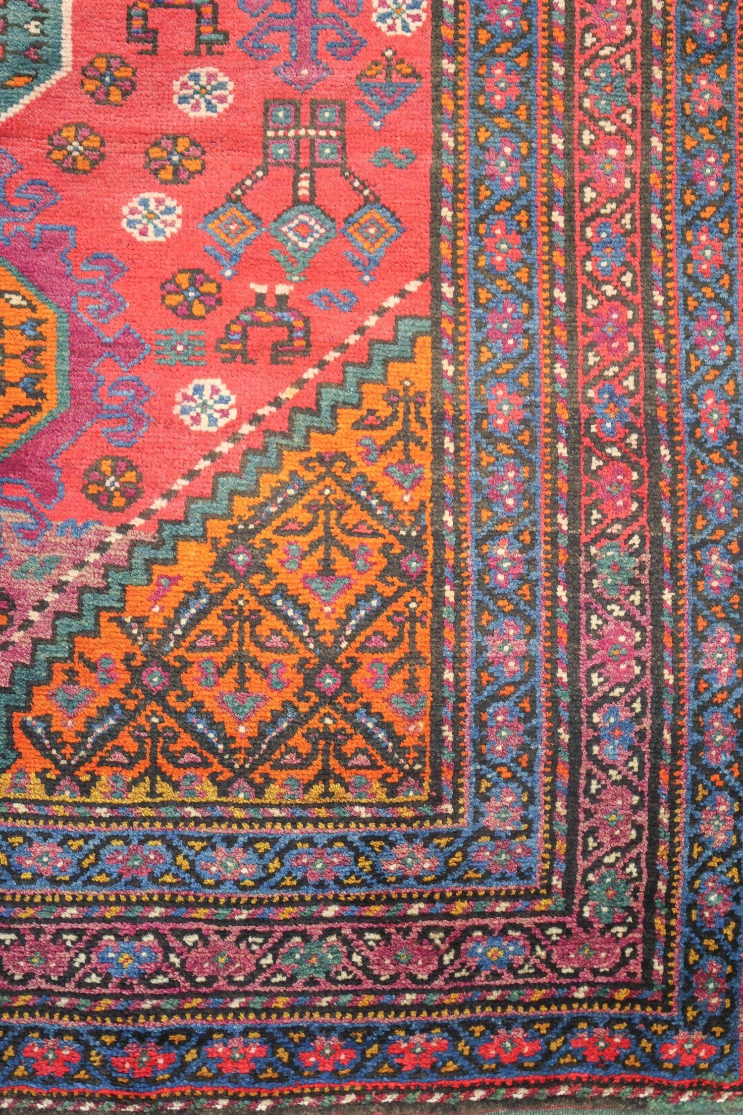 Detail of an antique Azeri rug, showcasing vibrant red, orange, and blue handwoven patterns.
