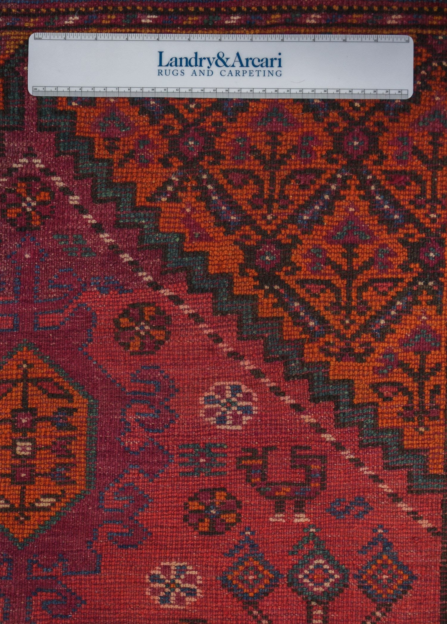 Close-up detail of antique Azeri rug, showcasing its intricate handwoven pattern in rich reds, oranges, and blues.
