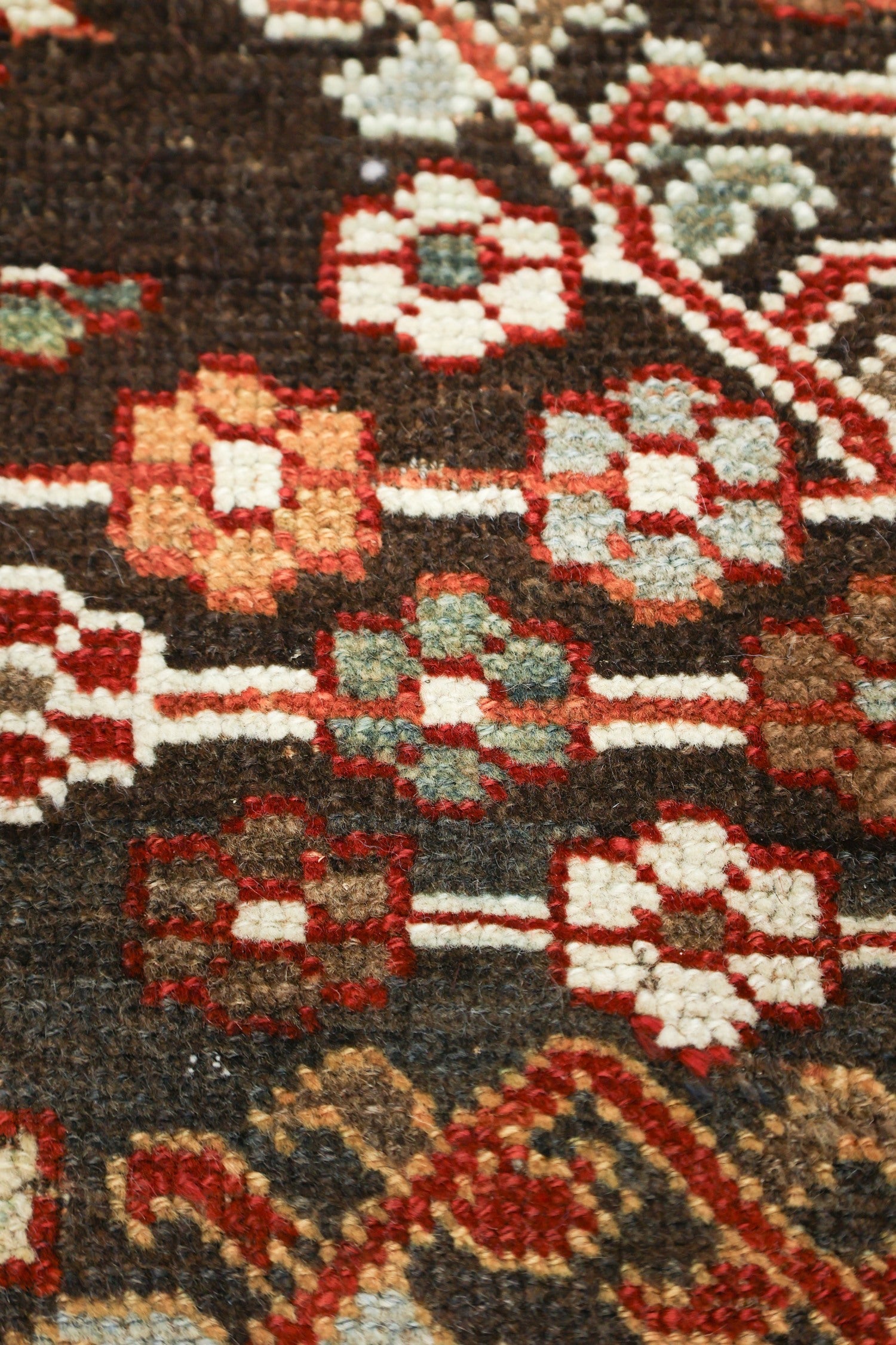 Close-up detail of a handwoven rug's intricate, multicolored pattern.
