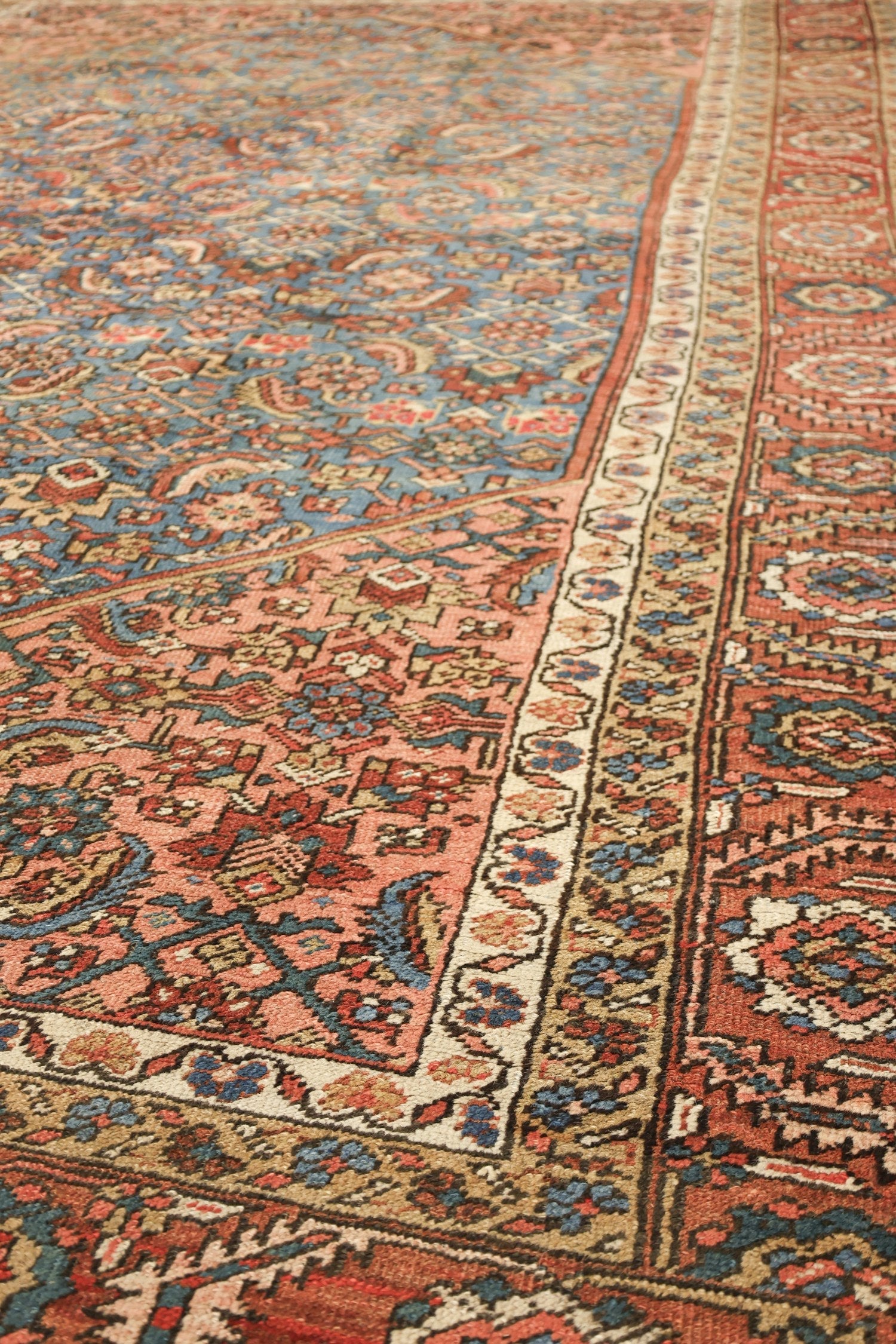 Handwoven tribal rug detail: intricate floral pattern in muted reds, blues, and beige tones.
