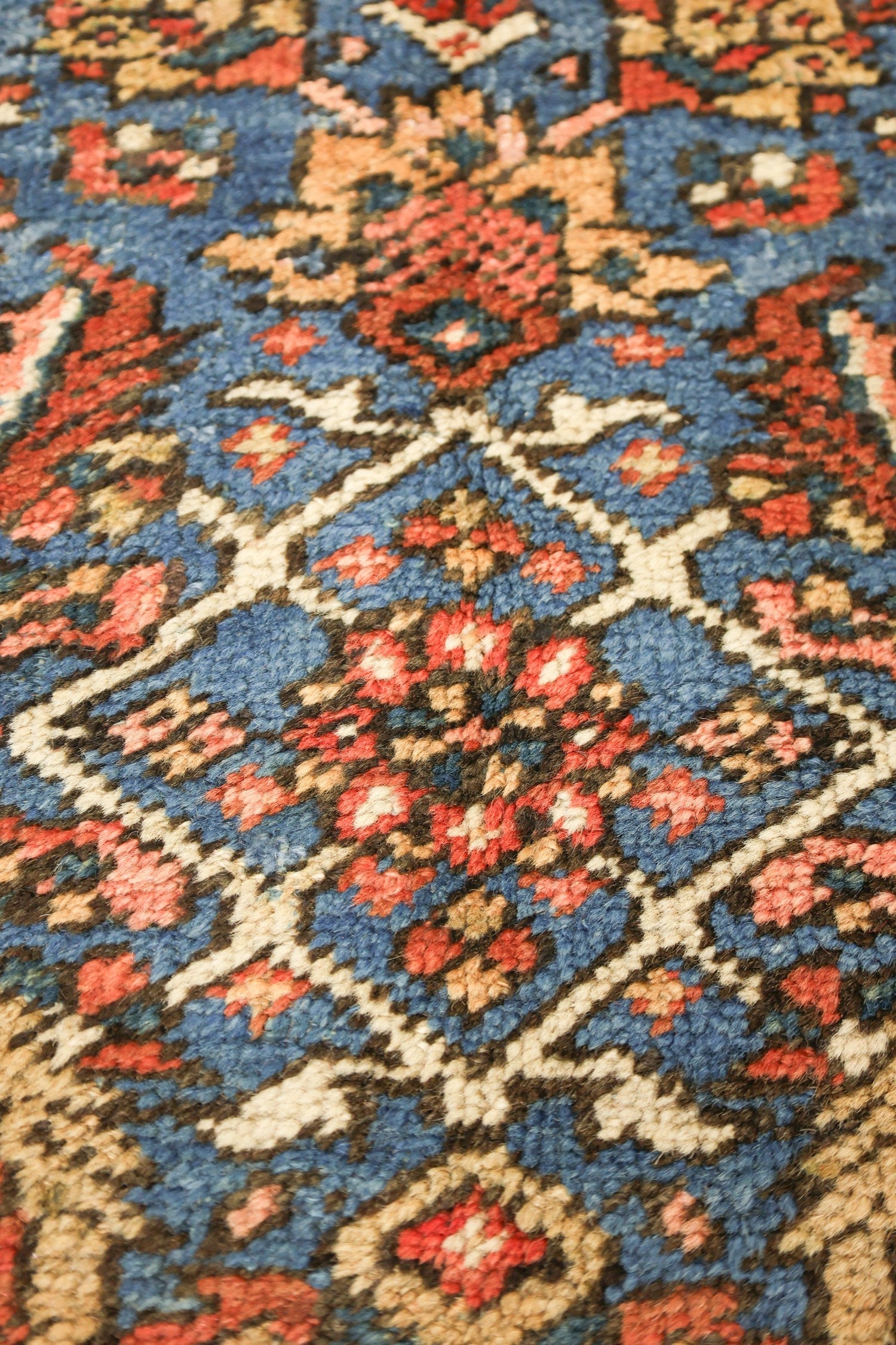 Close-up of an antique rug's handwoven, multicolored floral pattern.
