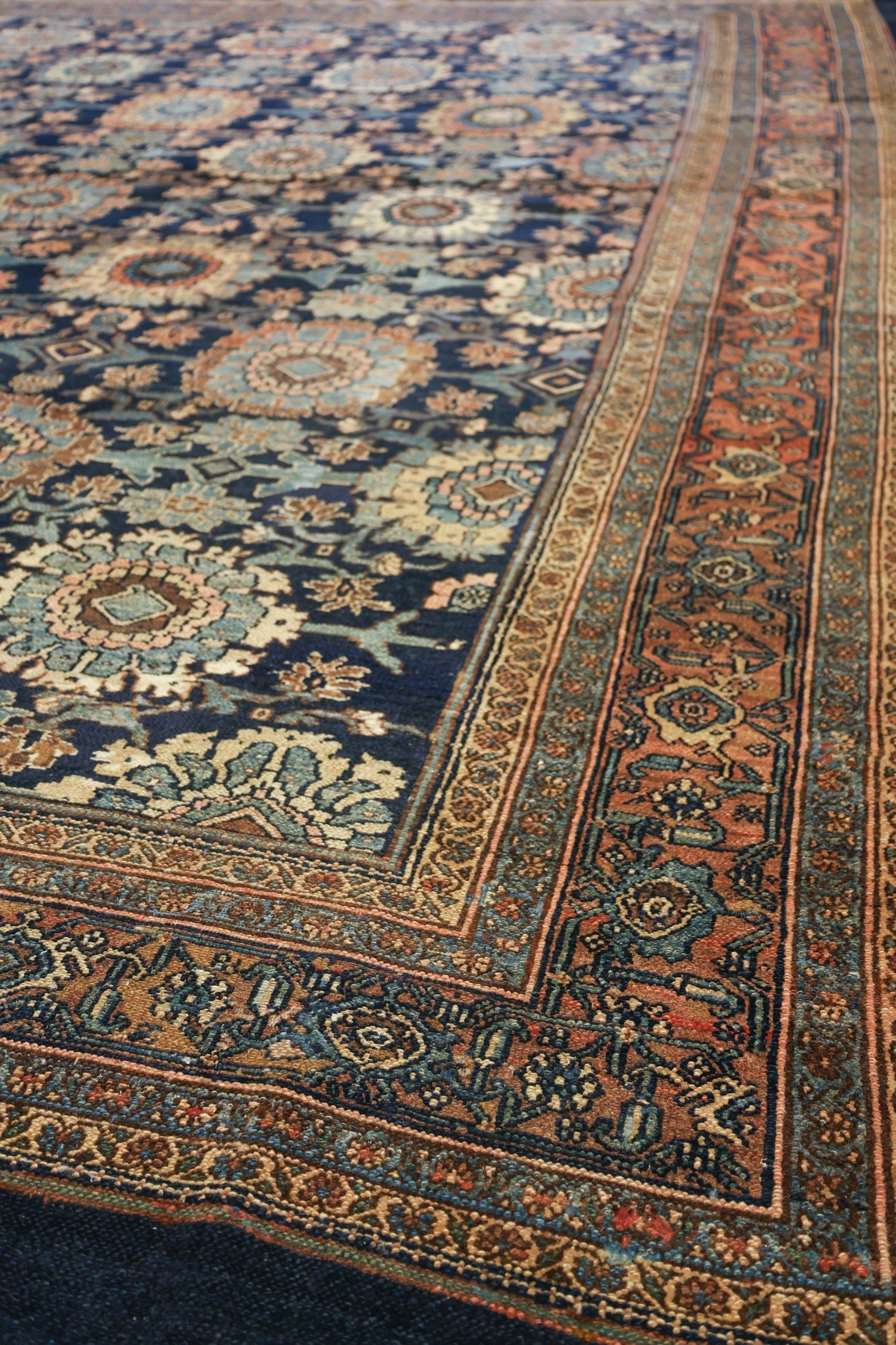 Handwoven tribal rug detail, showcasing intricate floral patterns in muted blues, oranges, and browns.
