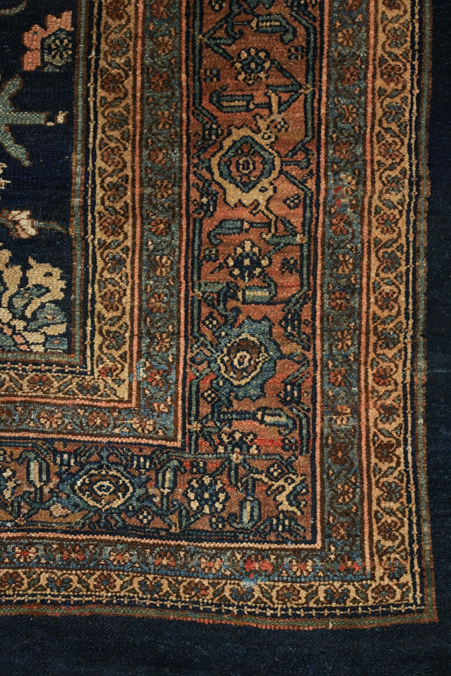 Intricate detail of an antique handwoven rug, showcasing rich, deep colors and traditional tribal patterns.
