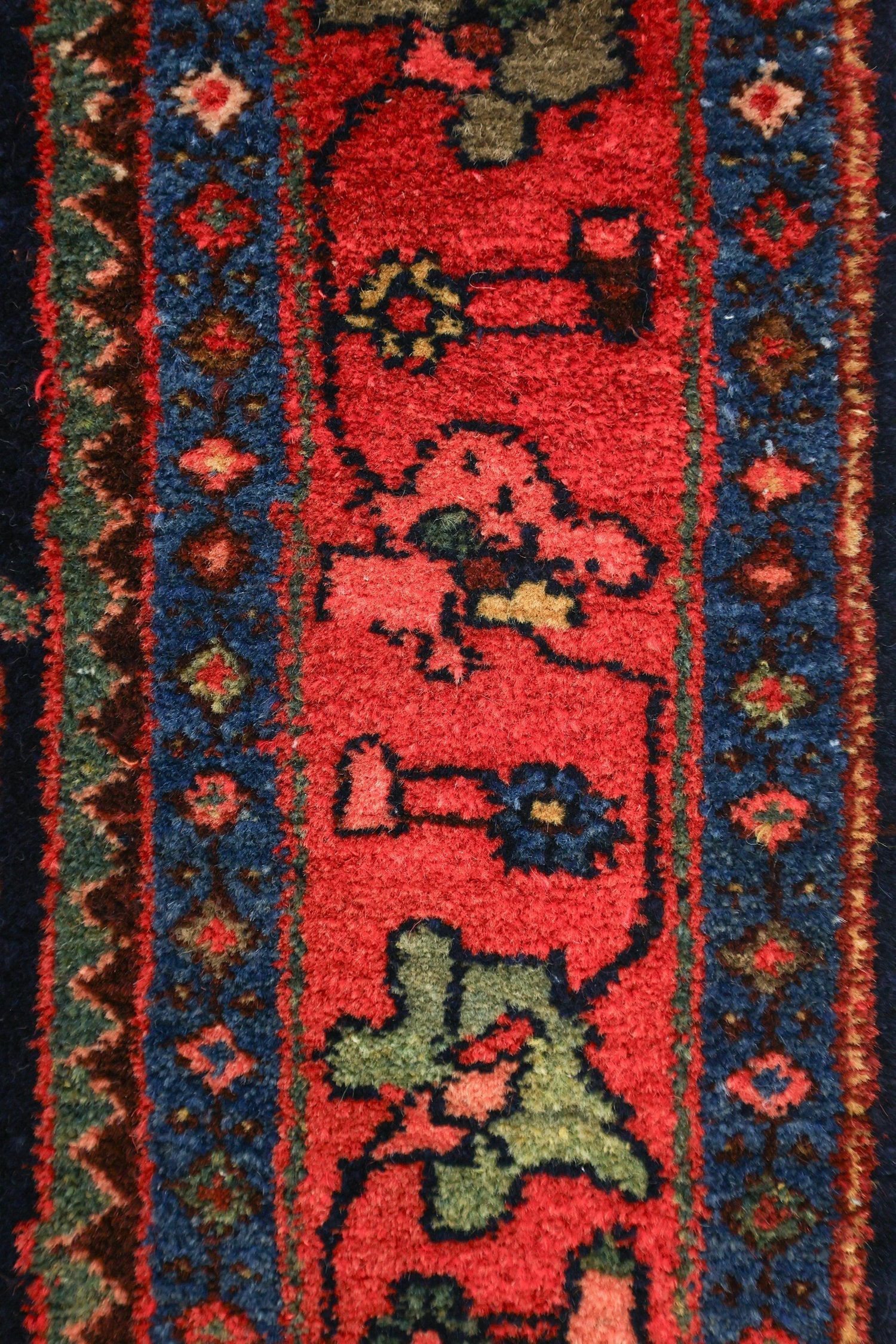 Close-up of a handwoven rug's detailed red and blue pattern.
