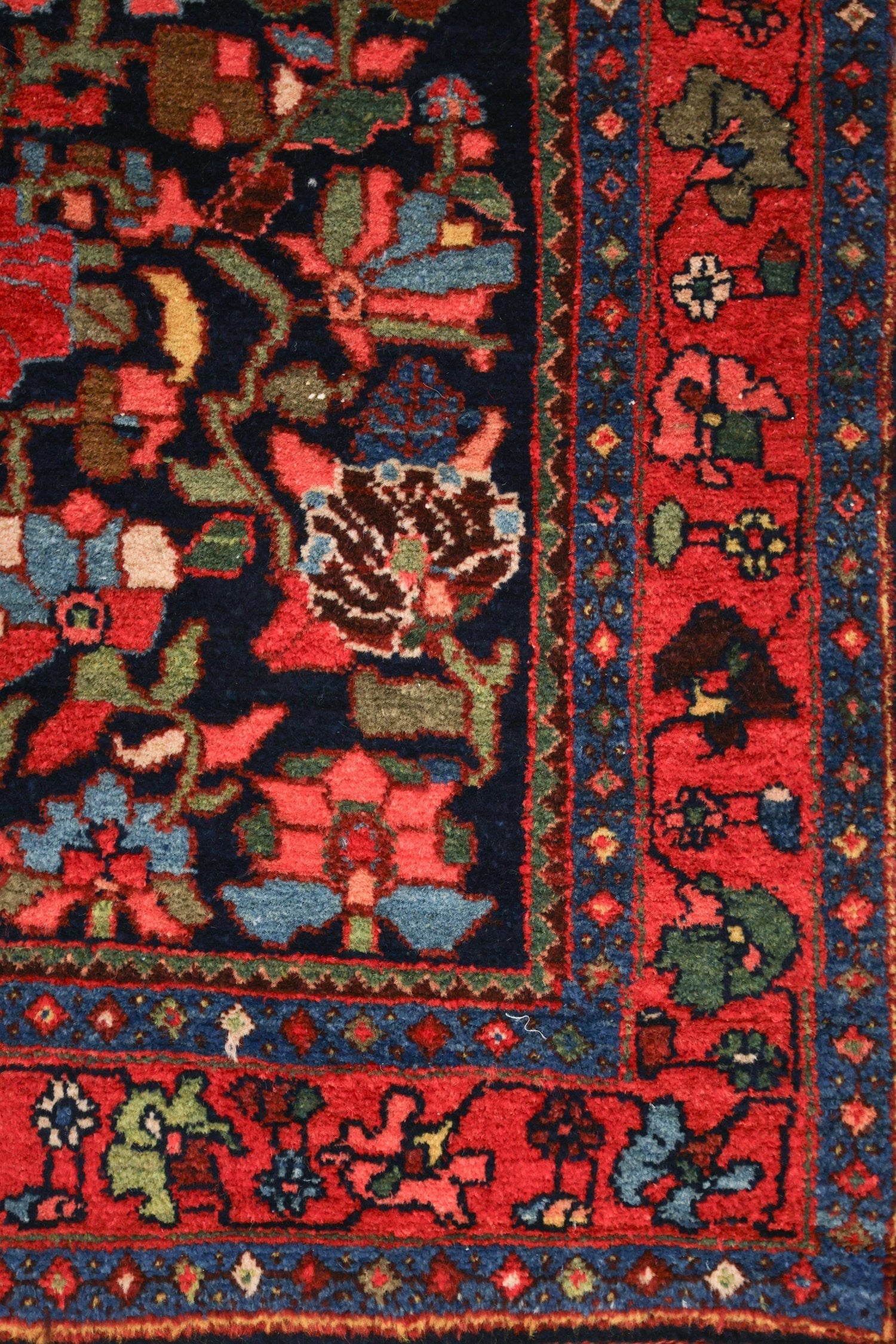 Detail of a handwoven rug with a red and navy blue floral pattern.
