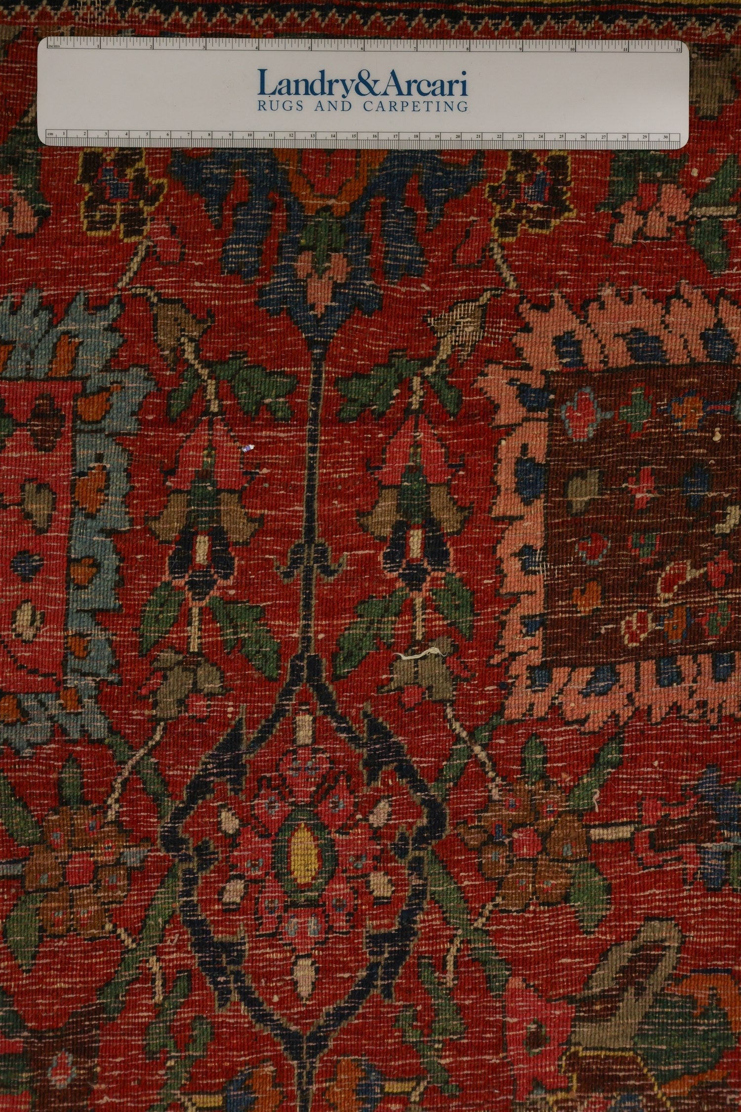 Detailed close-up of an antique Bijar rug, showcasing its intricate floral pattern in rich reds, blues, and greens.
