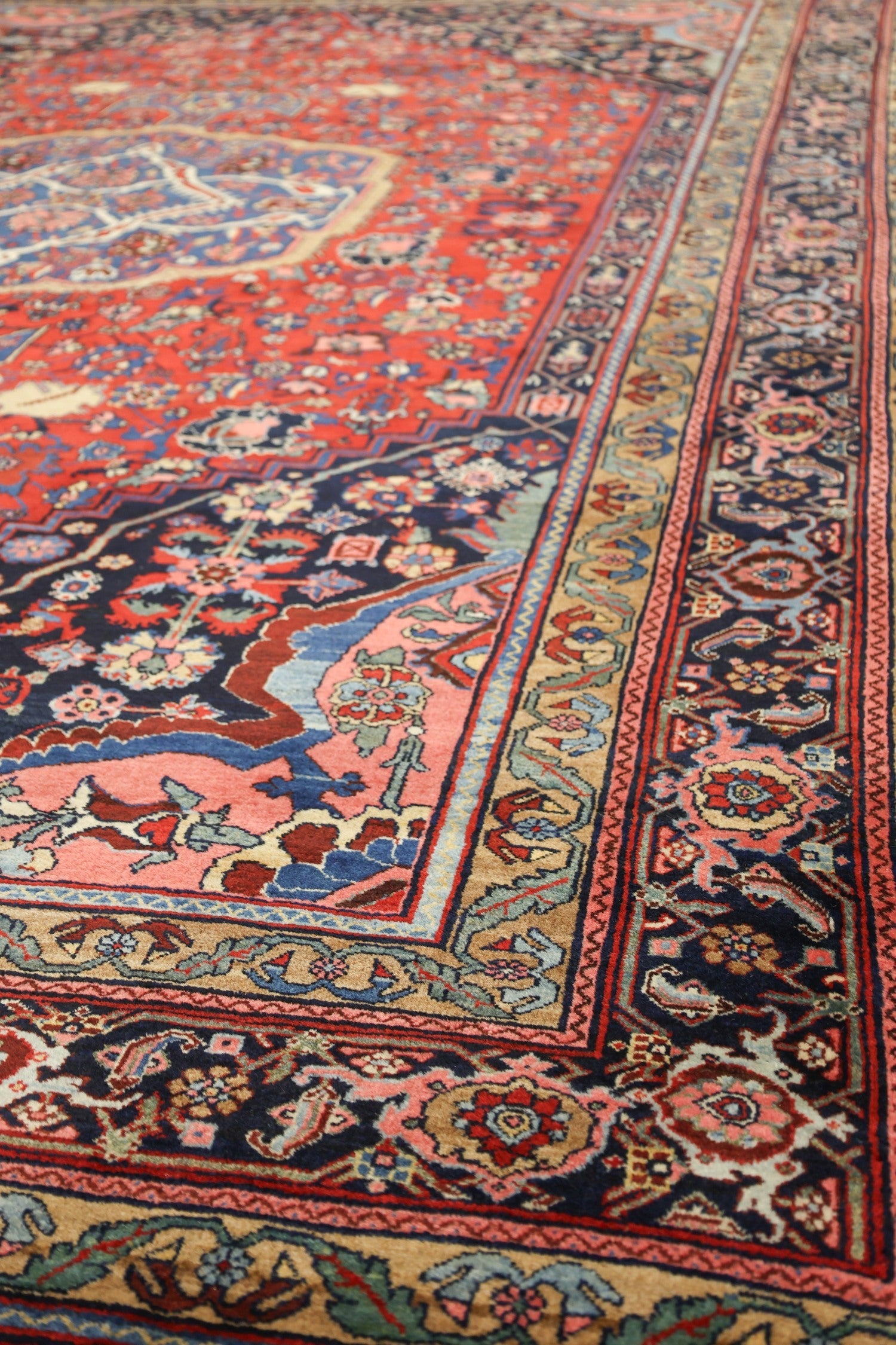 Detail of an antique Bijar rug, showcasing its intricate floral pattern in rich reds, blues, and beige.
