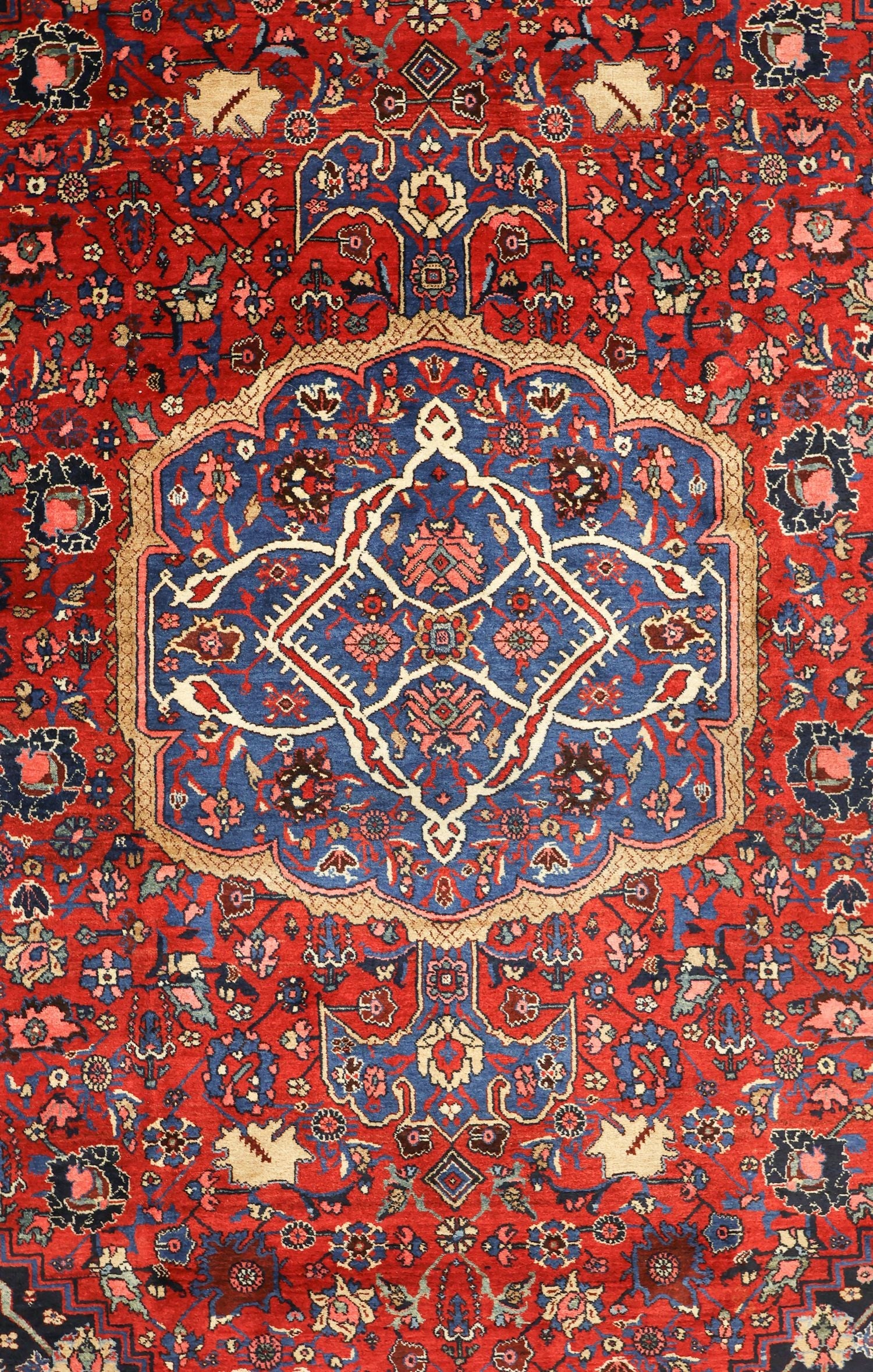 Intricate antique rug with a red and blue floral medallion, handwoven in a tribal design.
