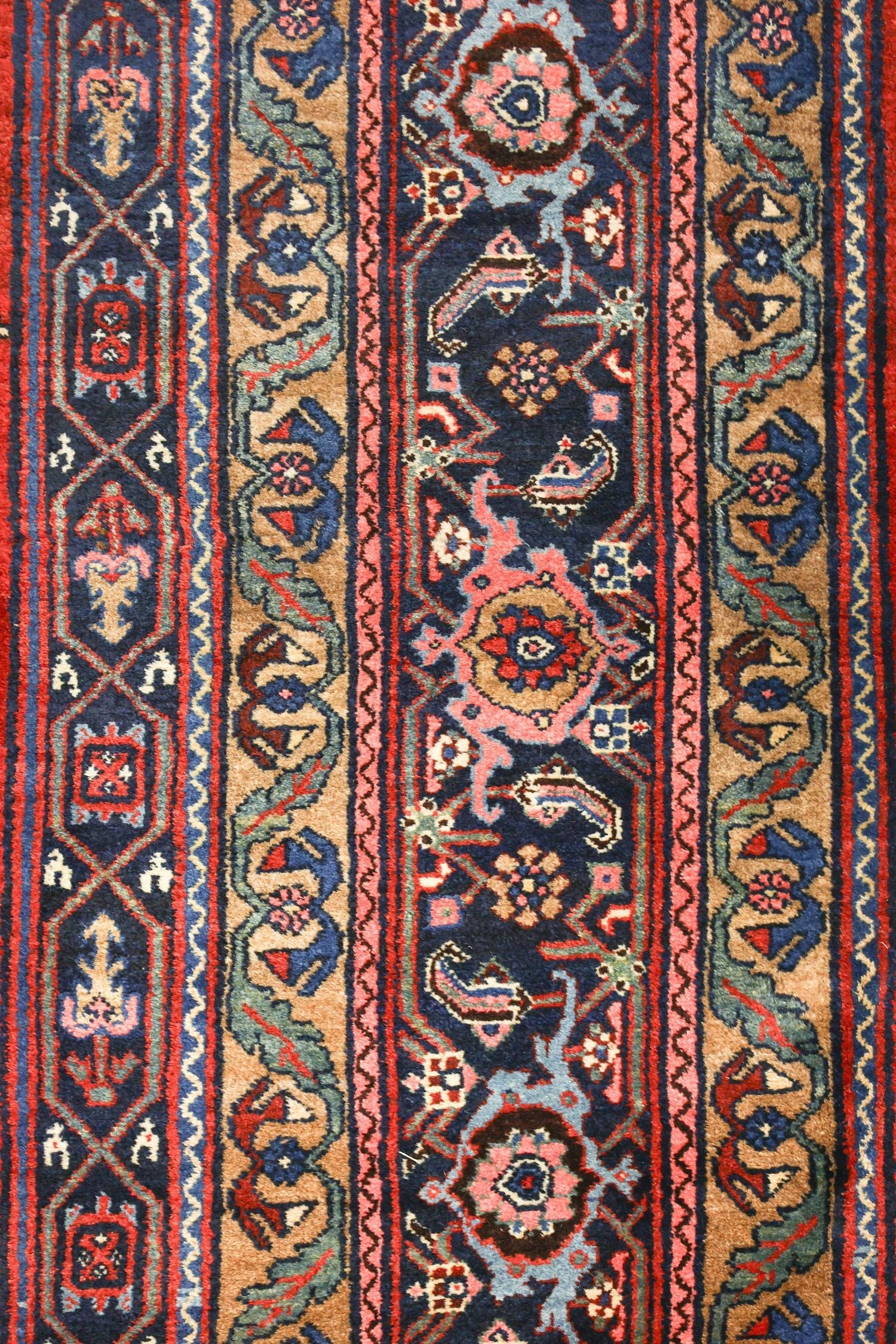 Detail of antique Bijar rug, showcasing intricate handwoven floral and geometric patterns in rich blues, reds, and tans.
