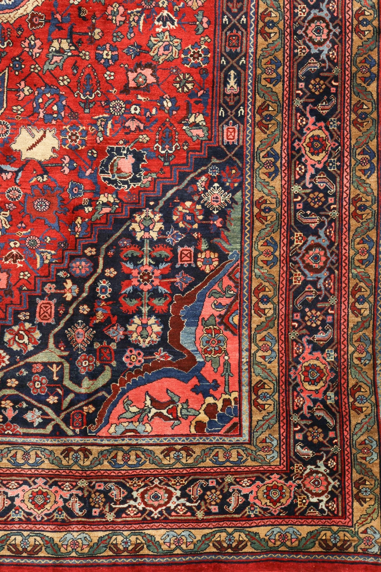 Detail of antique Bijar rug showcasing handwoven floral and geometric patterns in rich reds, blues, and golds.
