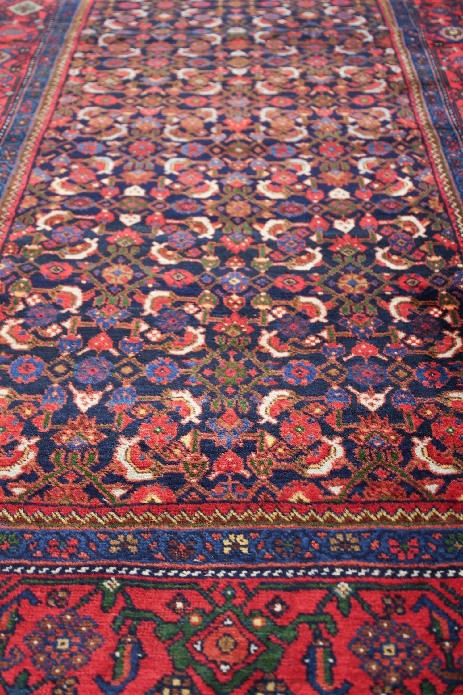 Handwoven tribal rug detail, showcasing a rich red and navy blue floral pattern.
