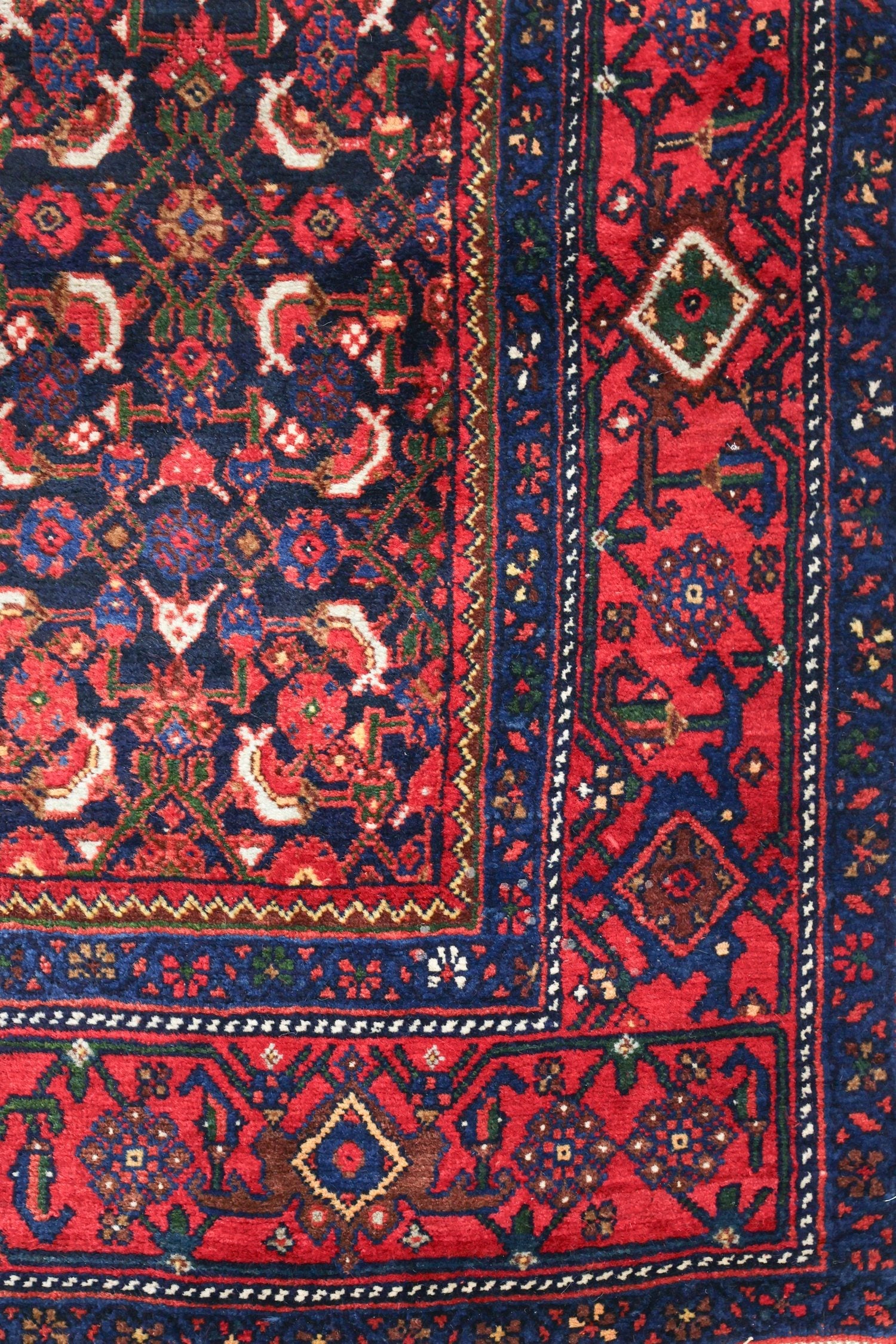 Detail of a handwoven tribal rug, showcasing intricate red and blue floral patterns.
