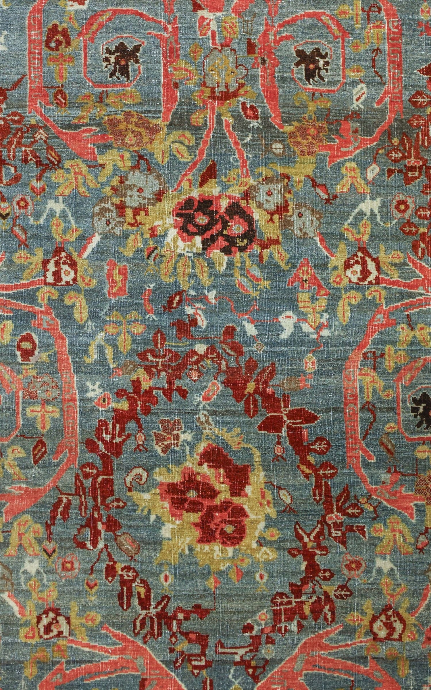 Detailed close-up of an antique Bijar rug's intricate, handwoven floral pattern in muted blues, reds, and golds.
