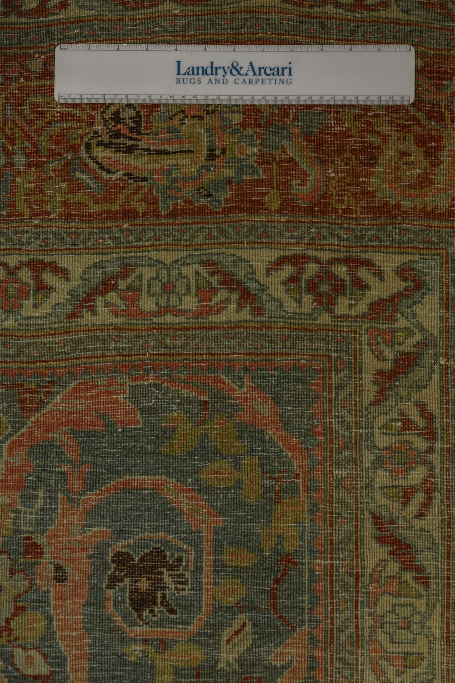 Close-up detail of antique Bijar rug's handwoven texture, showcasing muted greens, reds, and beige tones.
