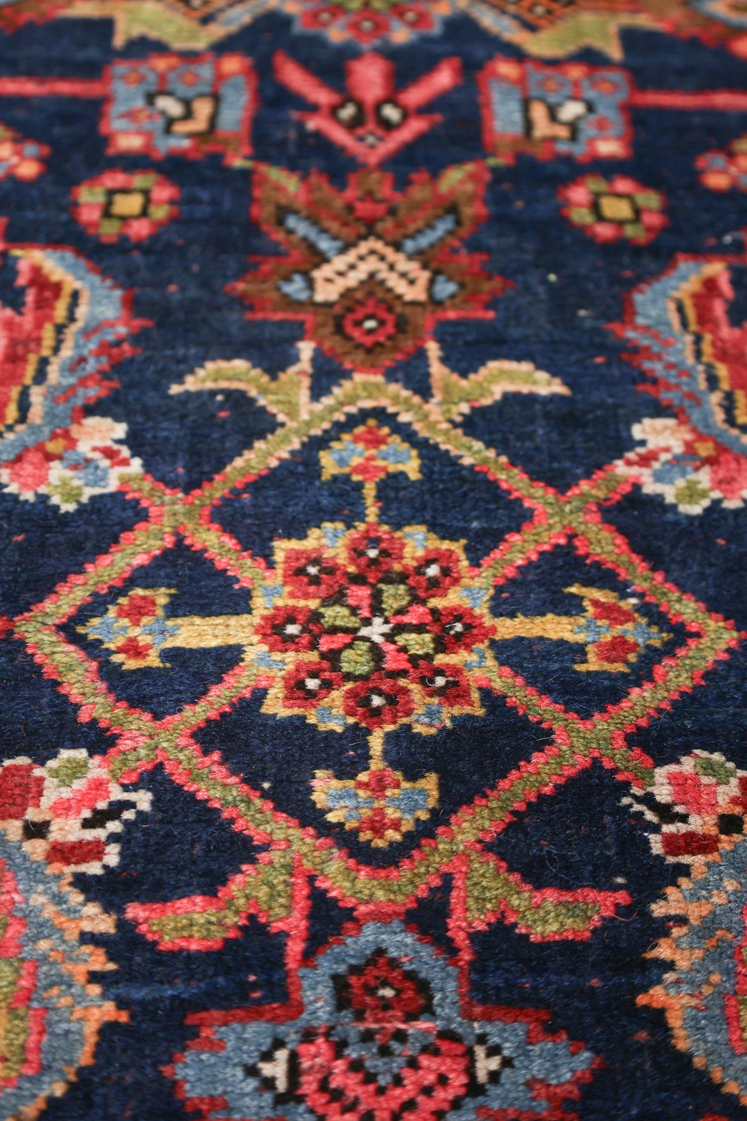 Intricate detail of a handwoven rug, showcasing a navy blue base with a vibrant, multicolored floral pattern.
