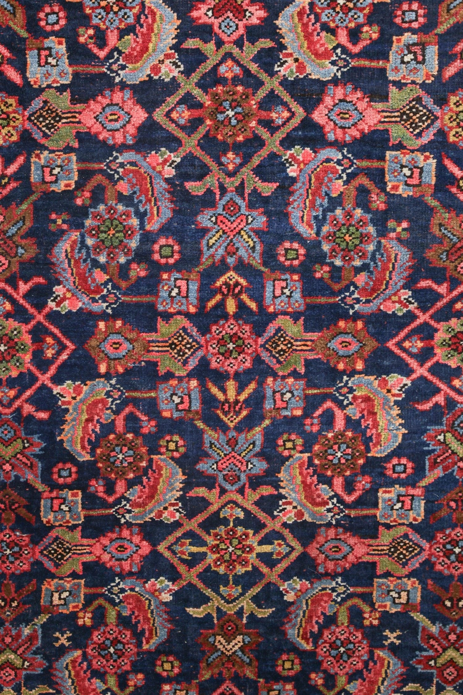 Intricate detail of a handwoven rug, showcasing a navy blue base with a vibrant floral and geometric pattern.
