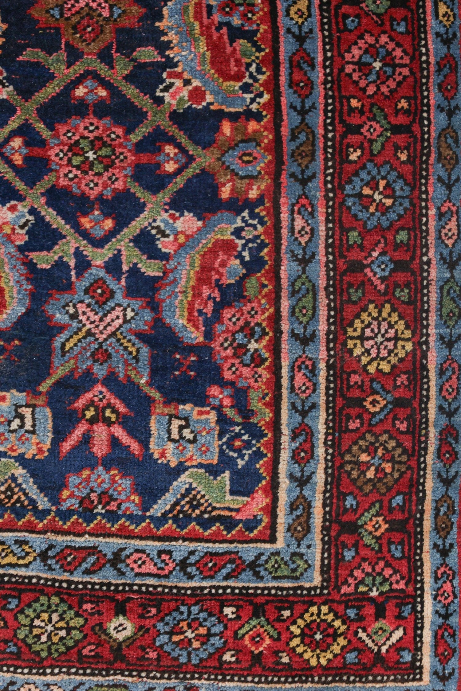 Antique handwoven rug detail: vibrant floral pattern in red, blue, and green.
