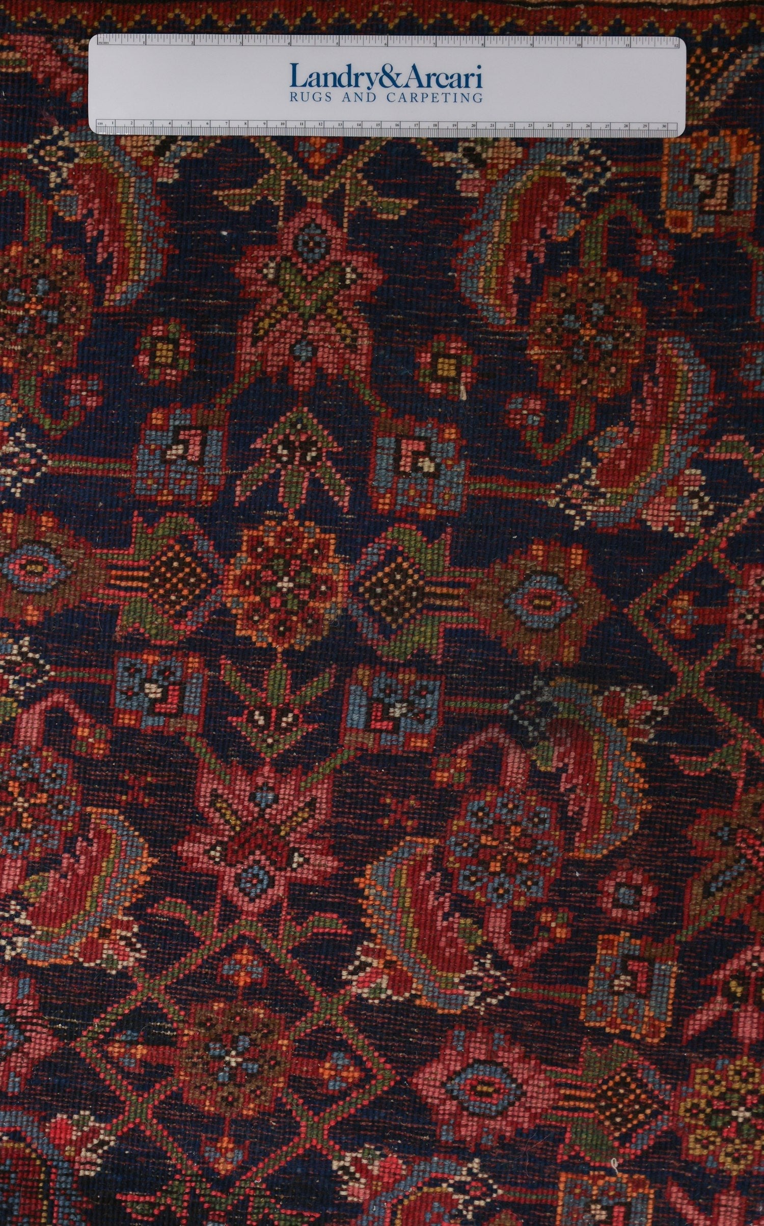 Detailed close-up of an antique Bijar rug's intricate, handwoven pattern in rich reds and blues.
