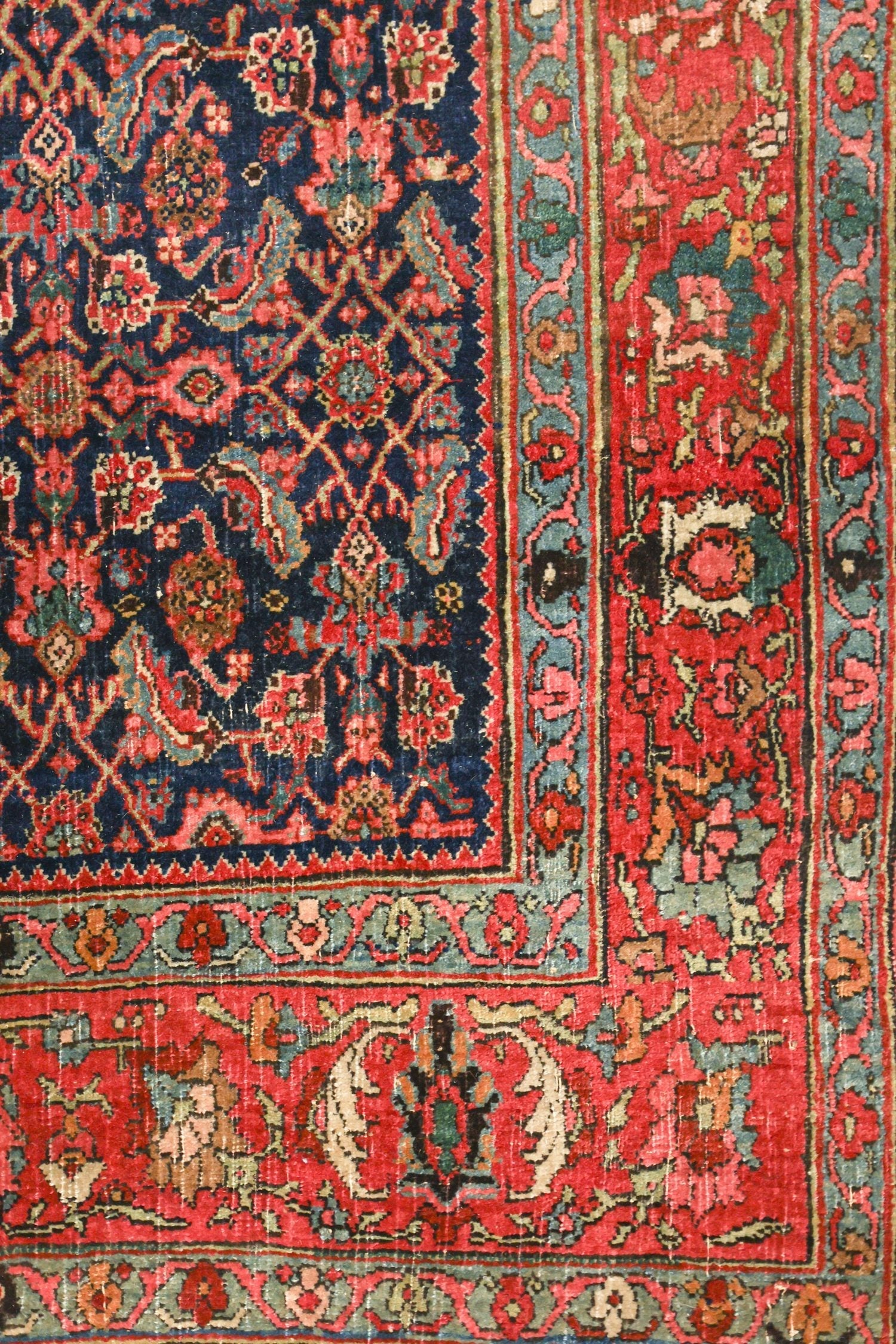 Detail of antique Bijar rug; intricate red and blue floral pattern, handwoven texture.
