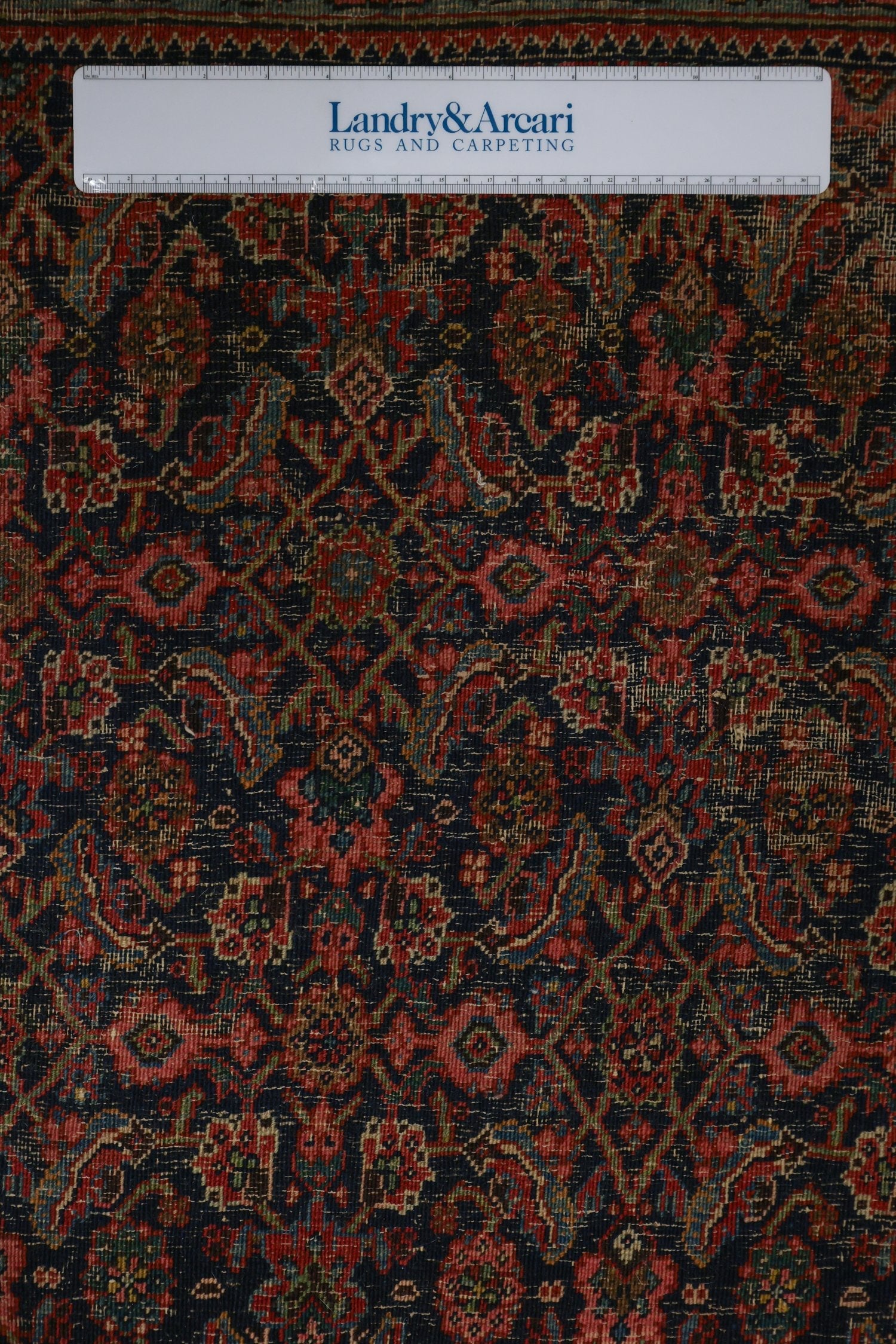 Detailed close-up of antique Bijar rug's intricate, handwoven pattern in deep reds and blues.
