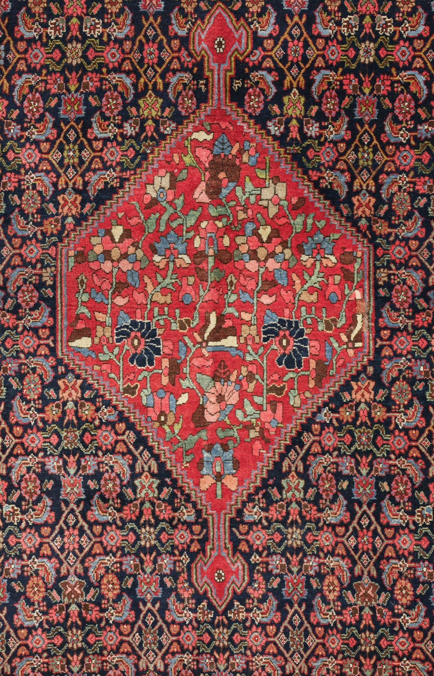 Intricate detail of a handwoven rug, showcasing a vibrant red and navy blue floral pattern.
