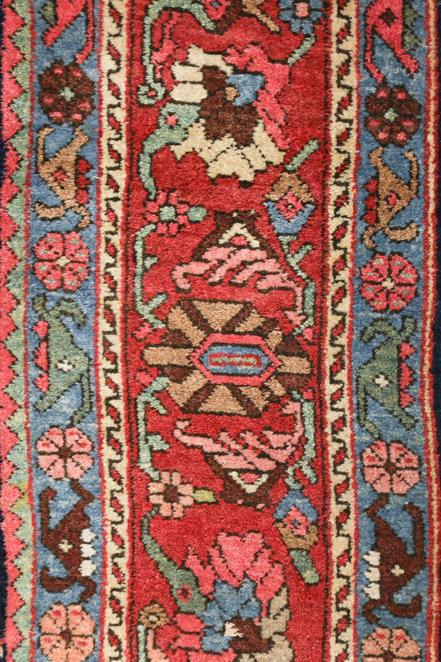 Handwoven rug detail: vibrant red, blue, and pink floral pattern, antique Bijar design.
